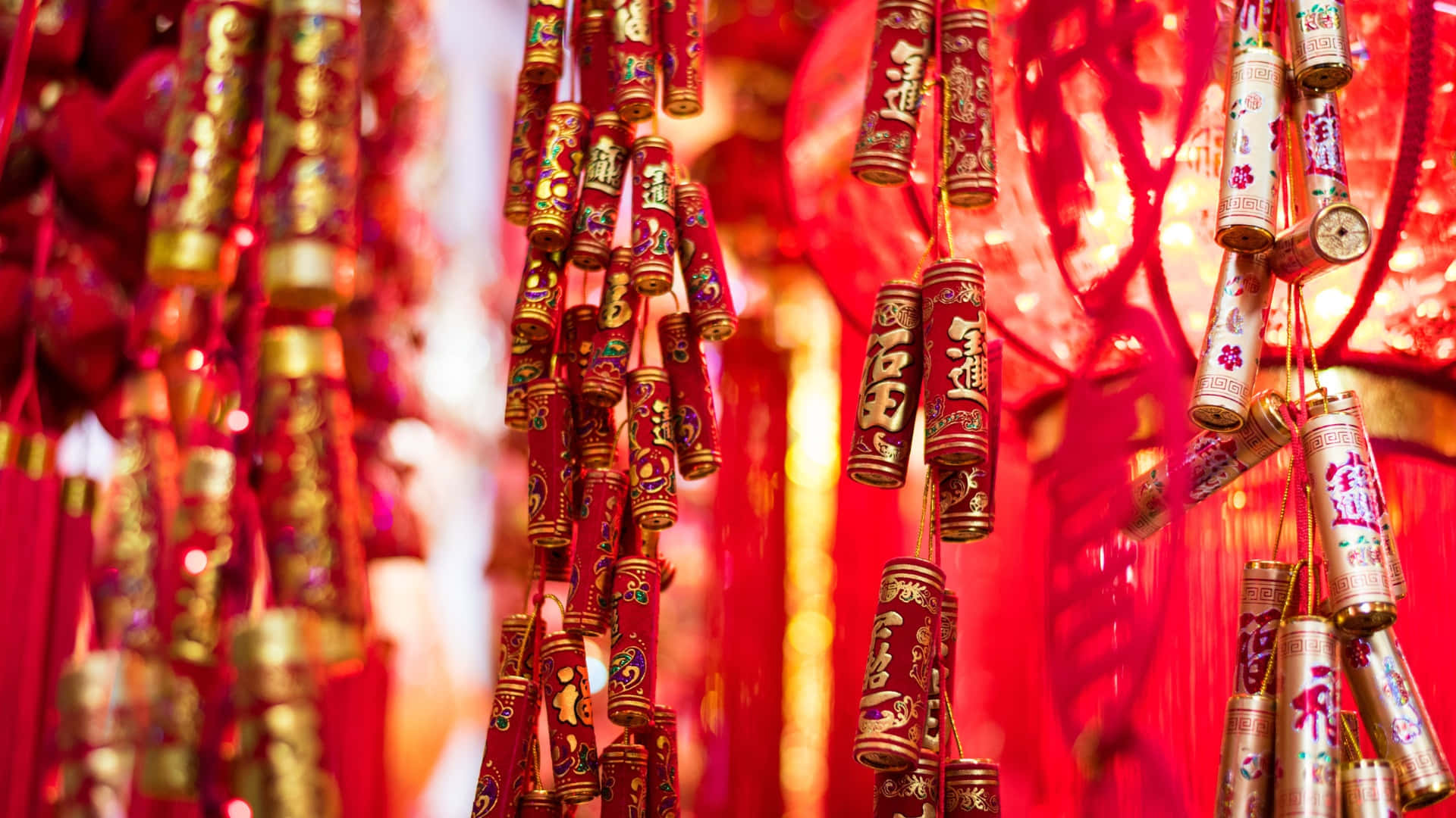  壁紙 — 鮮豔的紅色和金色中國鞭炮密集地掛在發光的燈籠上，慶祝農曆新年。