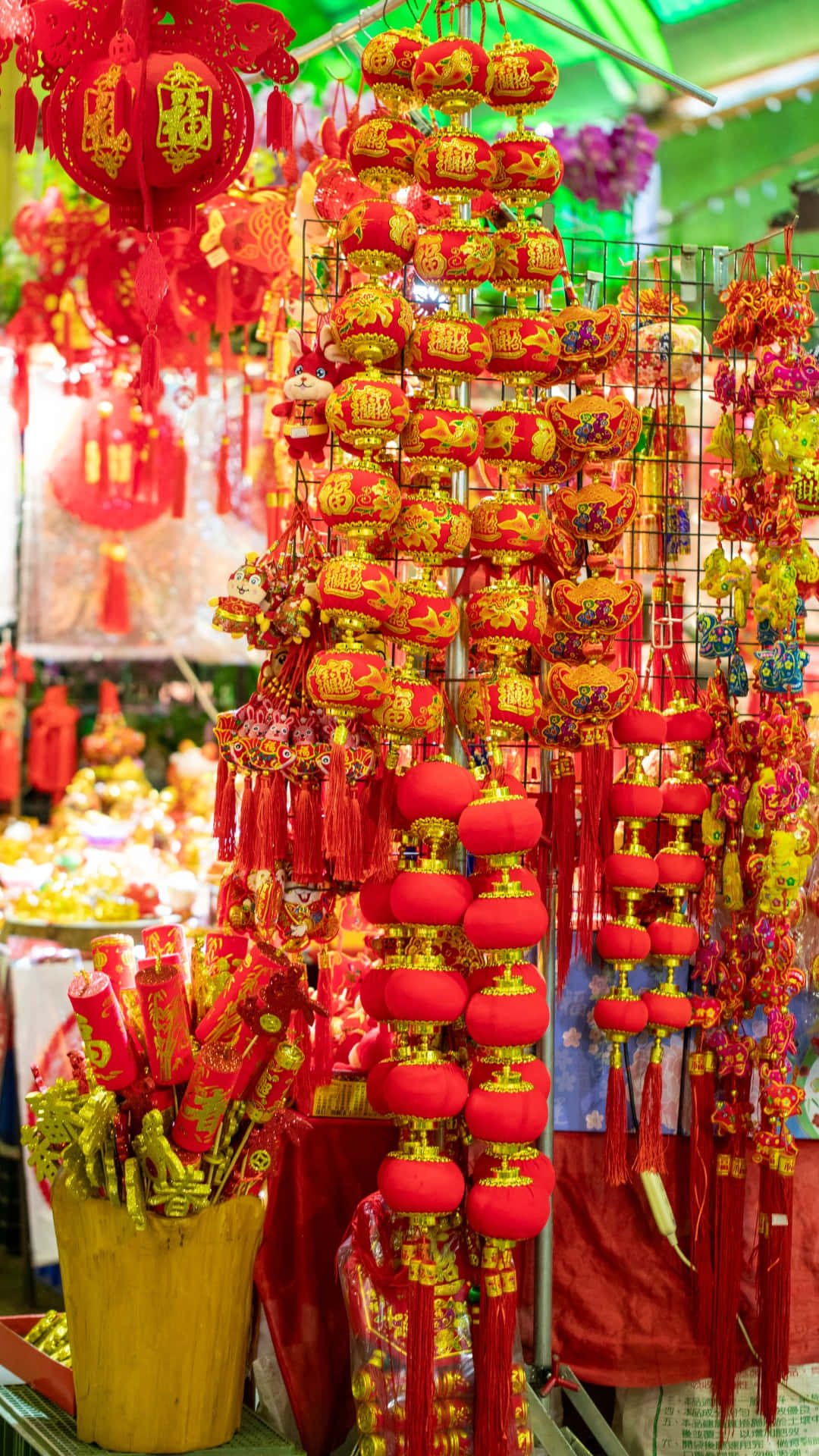  壁紙 — 鮮豔的紅色和金色中國燈籠和裝飾品密集地掛在一個節日市場攤位上，在明亮的燈光下閃閃發光。