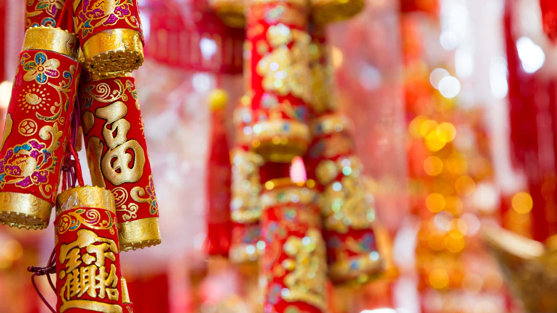  壁紙 — 鮮豔的紅色和金色中國新年鞭炮，飾有複雜的圖案和幸運字符，懸掛在節日慶祝中。