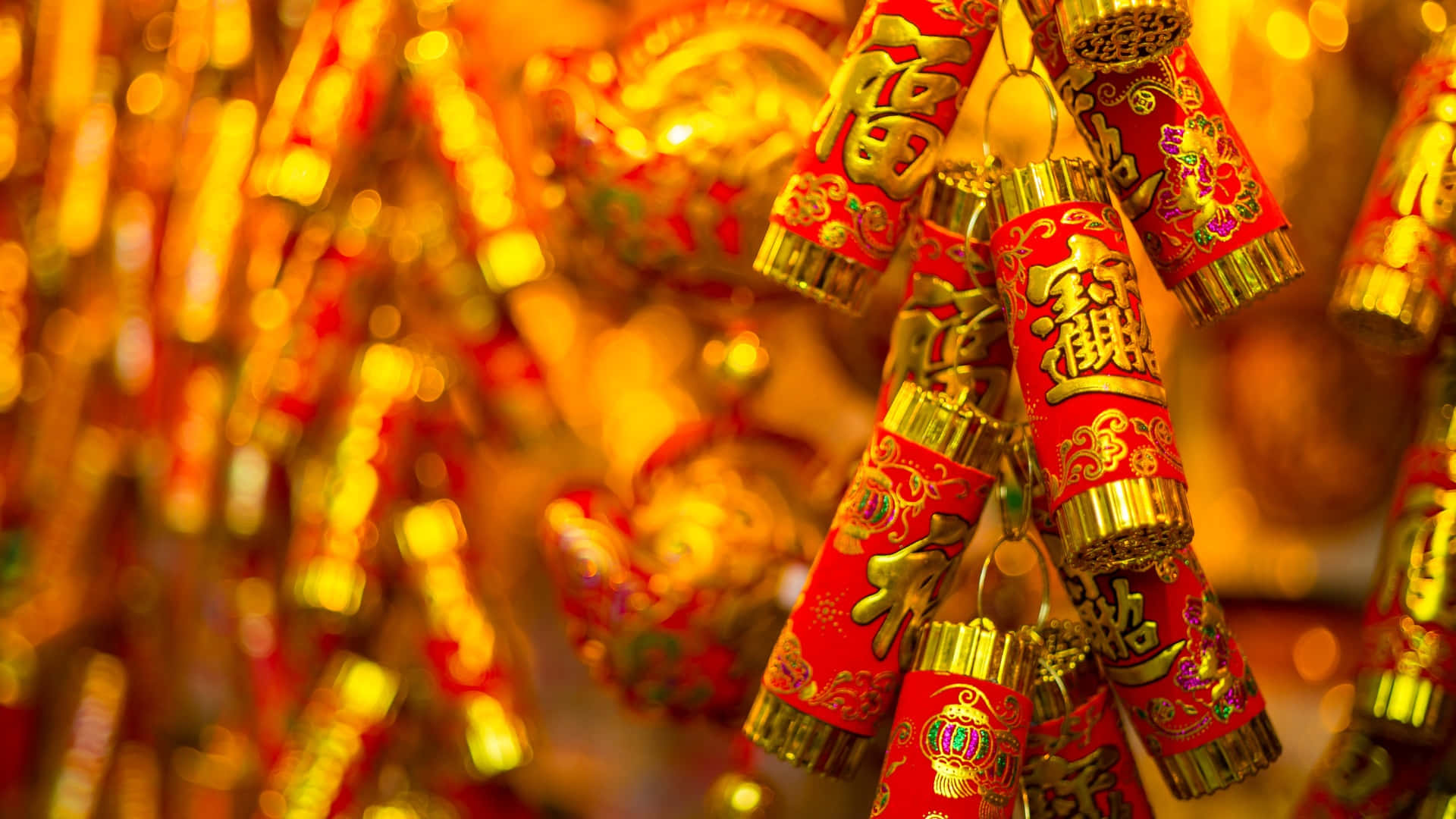  壁紙 — 鮮豔的紅色和金色中國新年鞭炮掛在節日簇中，背景是發光的散景。