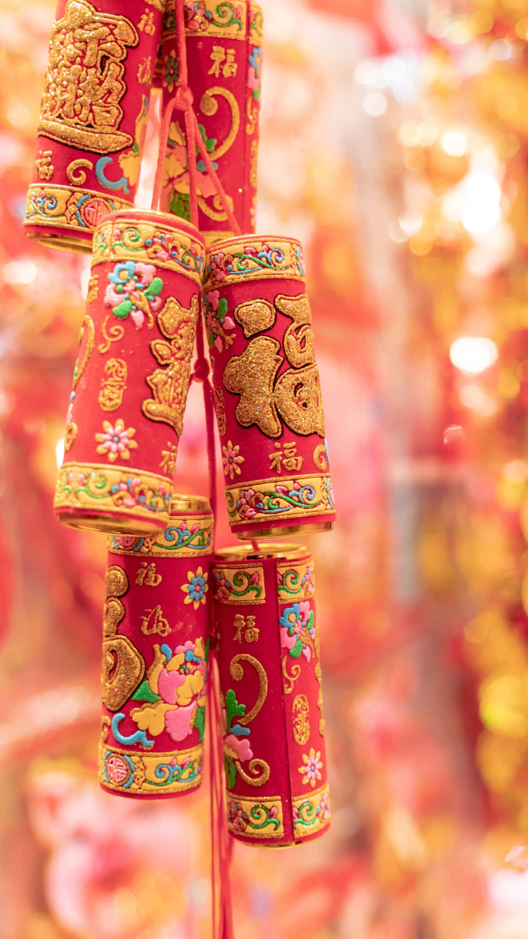  壁紙 — 鮮豔的紅色和金色中國新年紙燈籠，飾有精緻的花卉和字符設計，在模糊的散景背景下喜慶地懸掛著。
