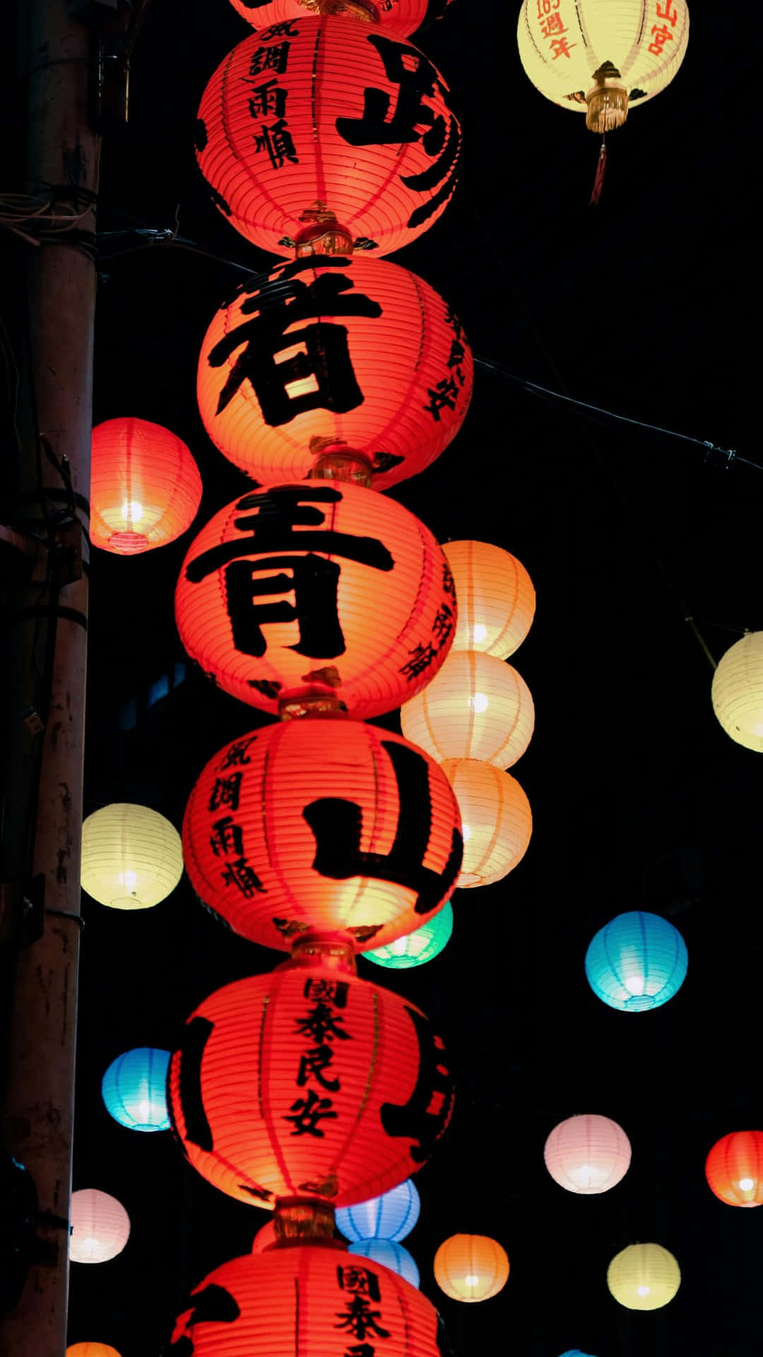  壁紙 — 鮮豔的紅色和白色紙燈籠，帶有黑色書法，在黑暗的夜空下閃耀，營造出節日街景。