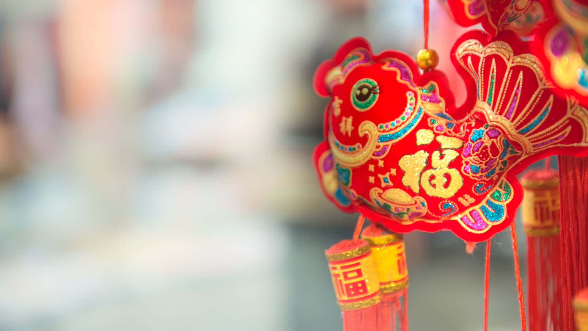  壁紙 — 一個鮮豔的紅色中國魚飾品，帶有金色和彩色刺繡，懸掛在柔和的模糊背景上。