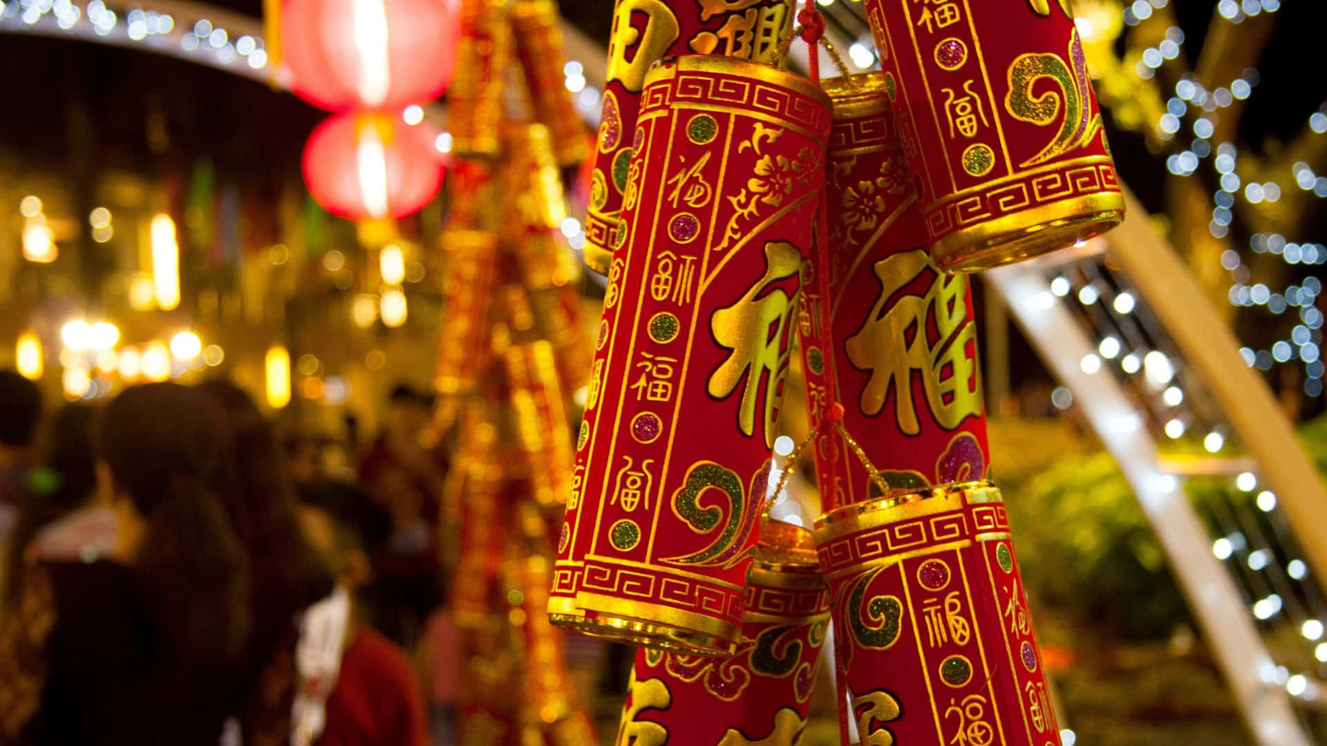  壁紙 — 鮮豔的紅色中國燈籠帶有金色書法，在模糊的節日夜景中溫暖地發光。