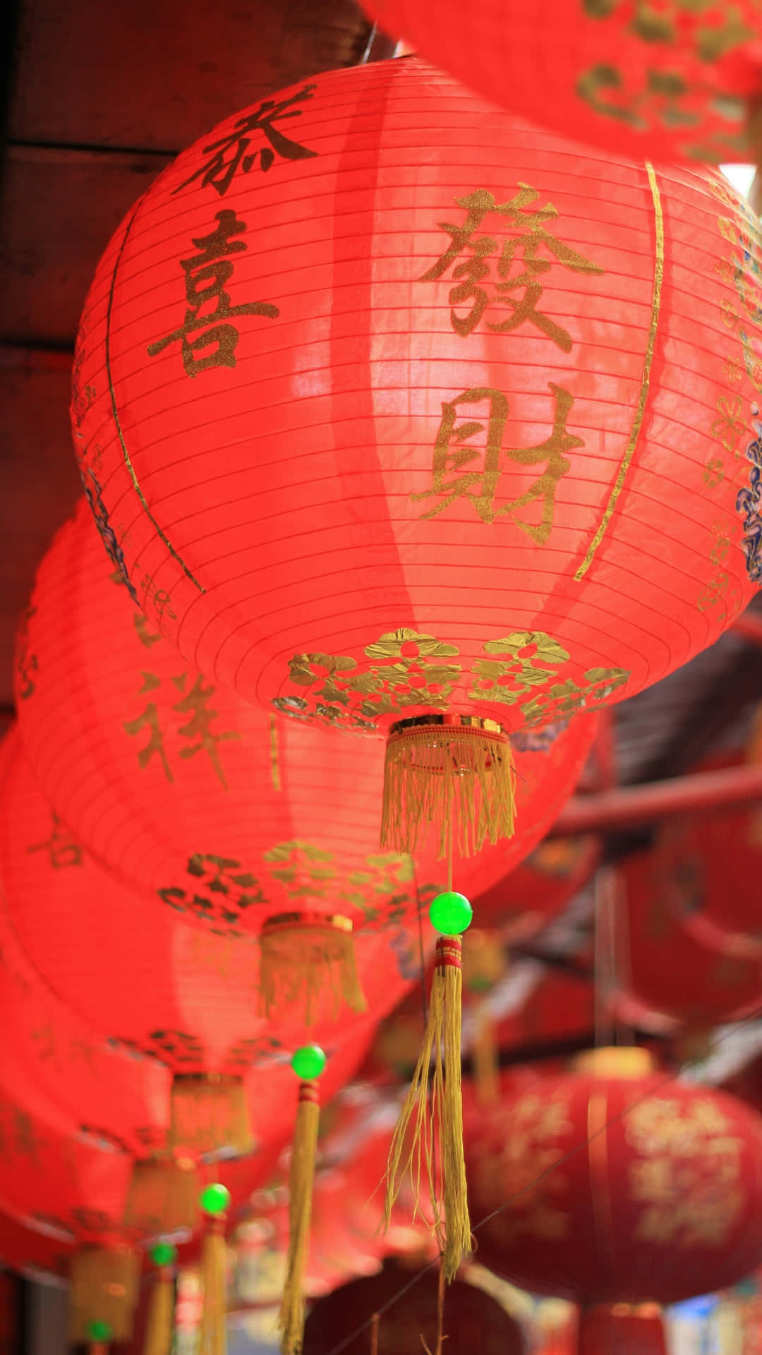  壁紙 — 鮮豔的紅色中國燈籠，帶有金色書法和流蘇，緊密地掛在一起，形成節日簇群。