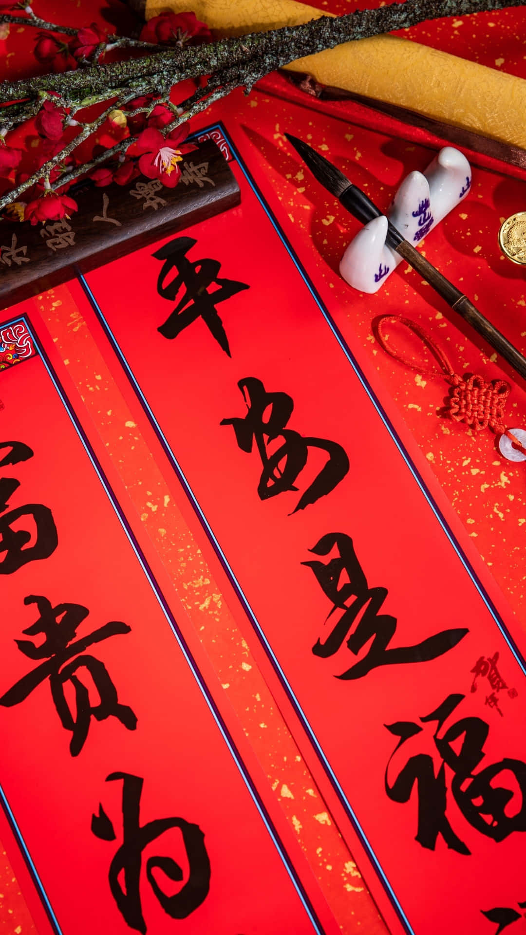  壁紙 — 鮮豔的紅色中國春聯，帶有黑色書法墨筆和裝飾性梅花，在節日表面上。