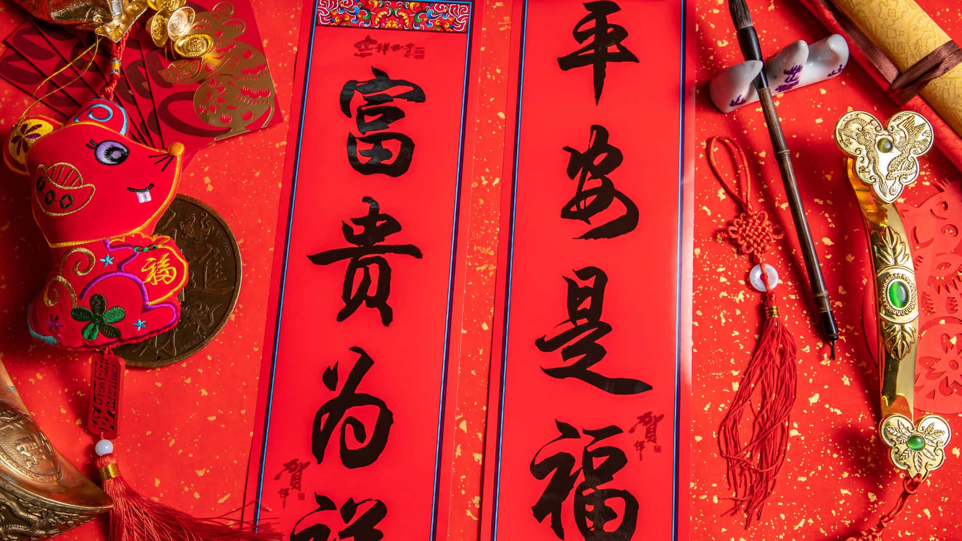  壁紙 — 鮮豔的紅色中國新年裝飾，包括書法卷軸、節日裝飾品和金色點綴，平放在閃亮的紅色背景上。