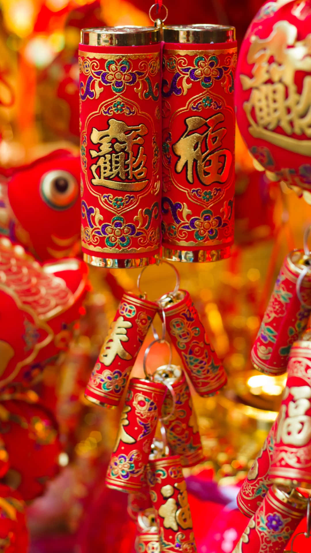  壁紙 — 鮮豔的紅色中國新年鞭炮，帶有金色字體，在模糊的類似裝飾背景中喜慶地懸掛著。