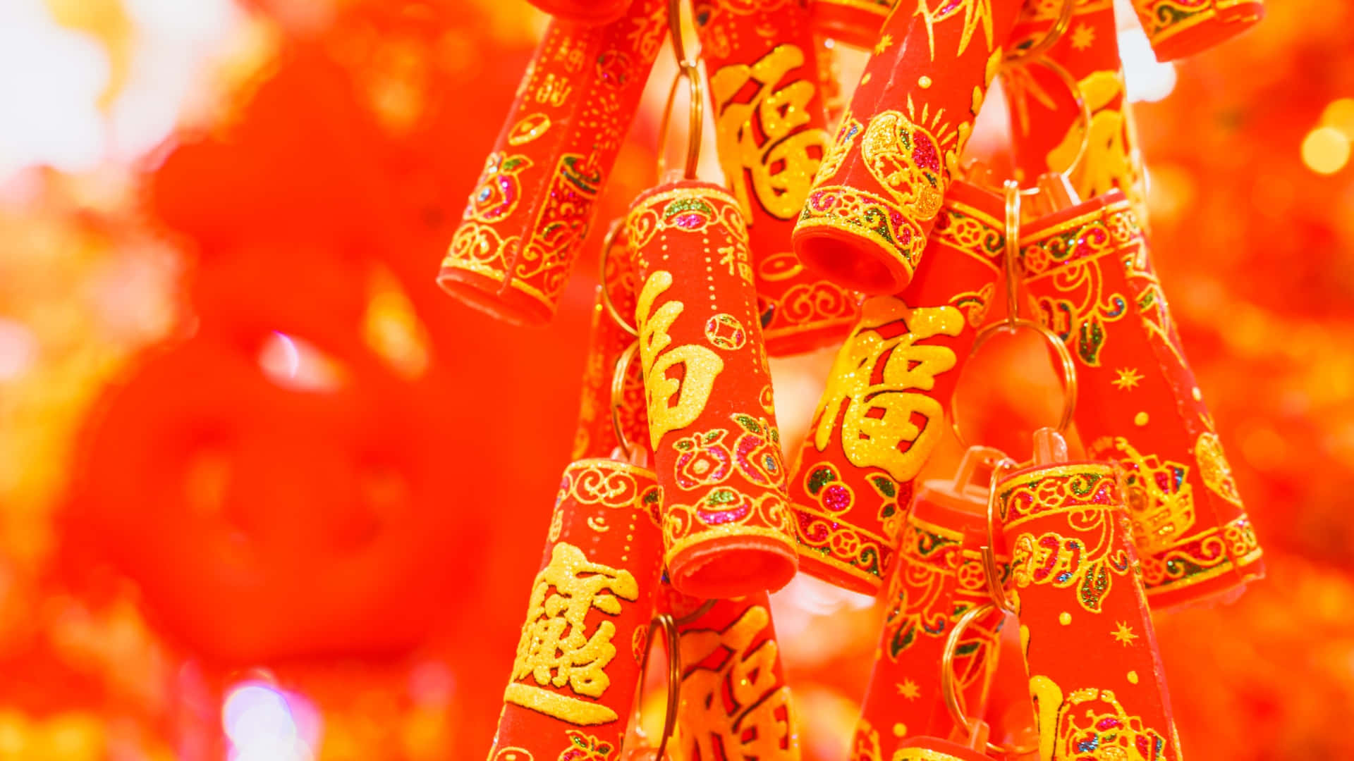  壁紙 — 鮮豔的紅色鞭炮帶有金色中文字，在發光的橙色散景背景上喜慶地懸掛著。