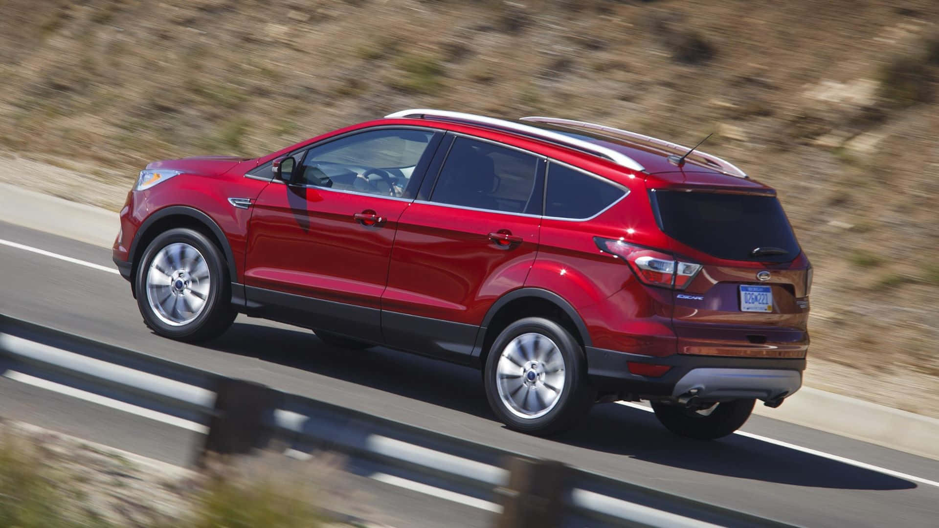 Ford Escape 桌布 壁紙 — 一輛鮮紅色的福特Escape SUV在陽光明媚的高速公路上行駛，模糊的山丘飛馳而過。