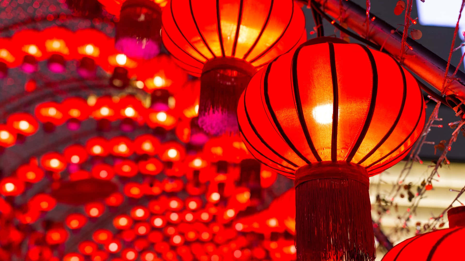  壁紙 — 鮮豔的紅色燈籠在模糊的節日背景下溫暖地發光，營造出豐富紋理的慶祝場景。