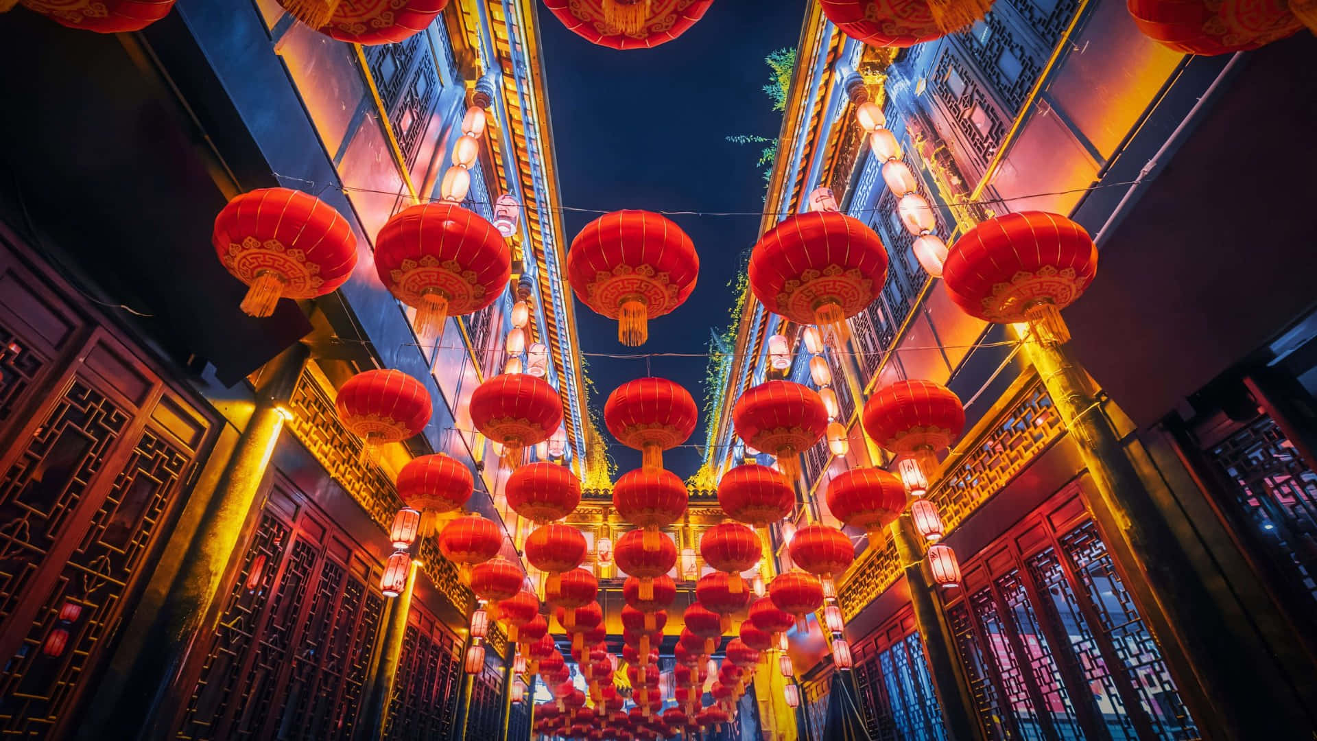  壁紙 — 鮮豔的紅色燈籠在深藍色夜空下，於傳統中國小巷中溫暖地發光。