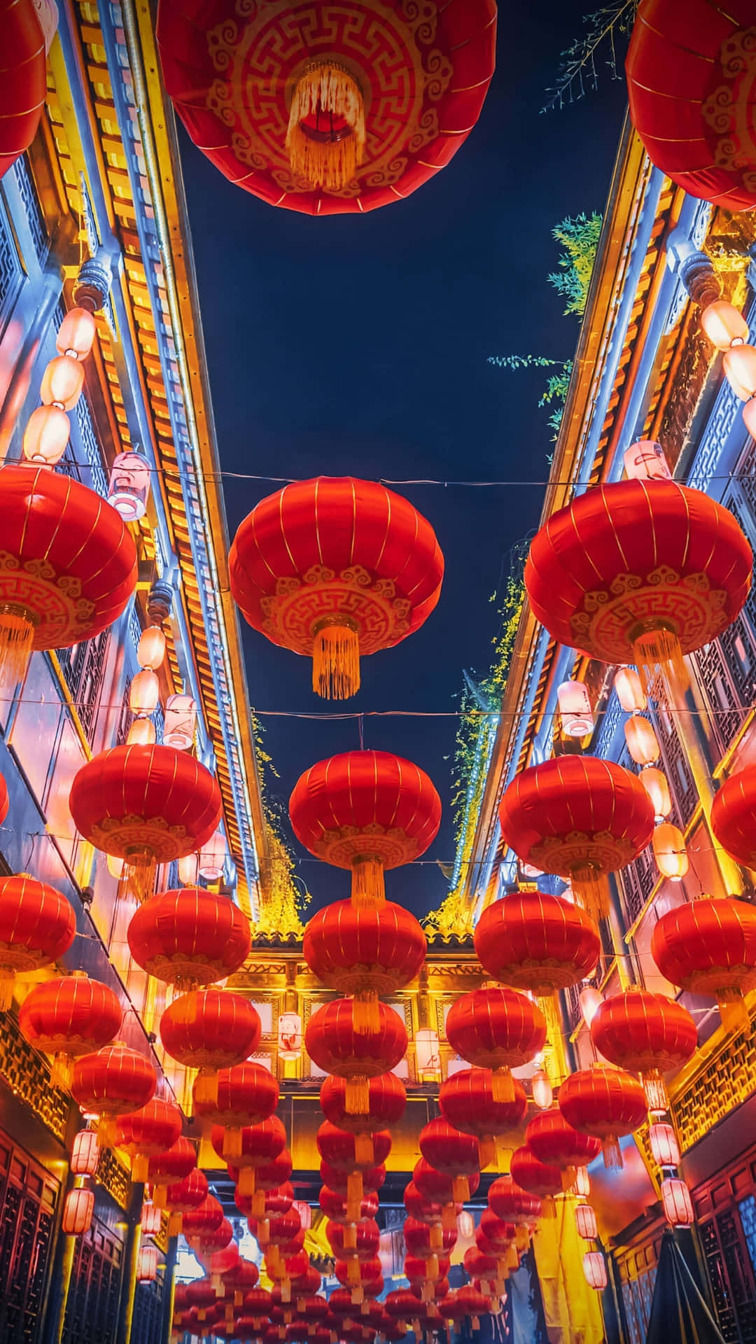  壁紙 — 鮮豔的紅色燈籠在傳統中國小巷中，對著深藍色的夜空溫暖地發光。