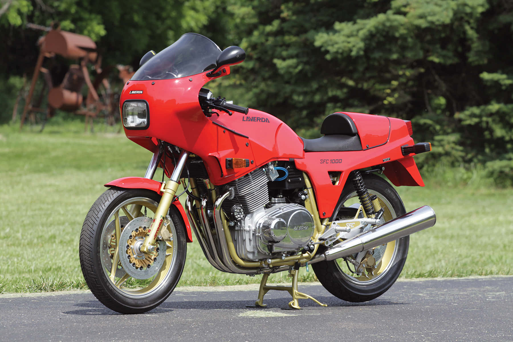  壁紙 — 一架鮮紅色嘅Laverda SFC 1000電單車，配金色前叉同鉻合金裝飾，企喺鋪砌嘅路旁邊，旁邊係茂盛嘅綠色草坪。