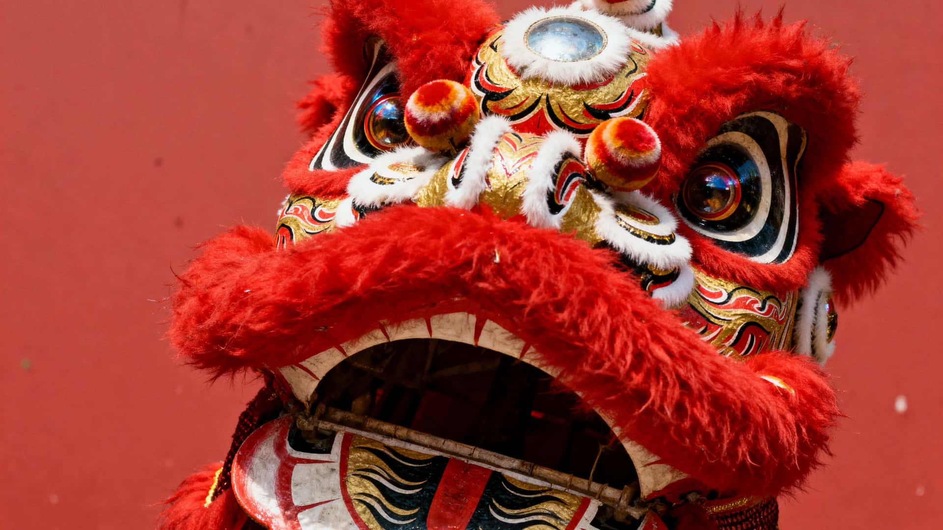  壁紙 — 鮮豔的紅色舞獅服裝，帶有金色和白色的精緻圖案，背景為純紅色。