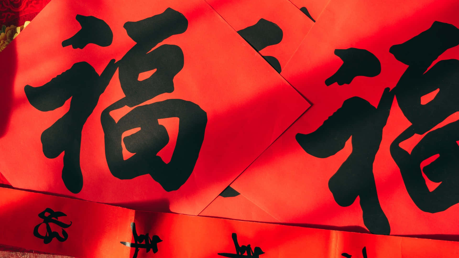  壁紙 — 鮮豔的紅紙上飾有粗體黑色中文書法字，寓意好運和慶祝。