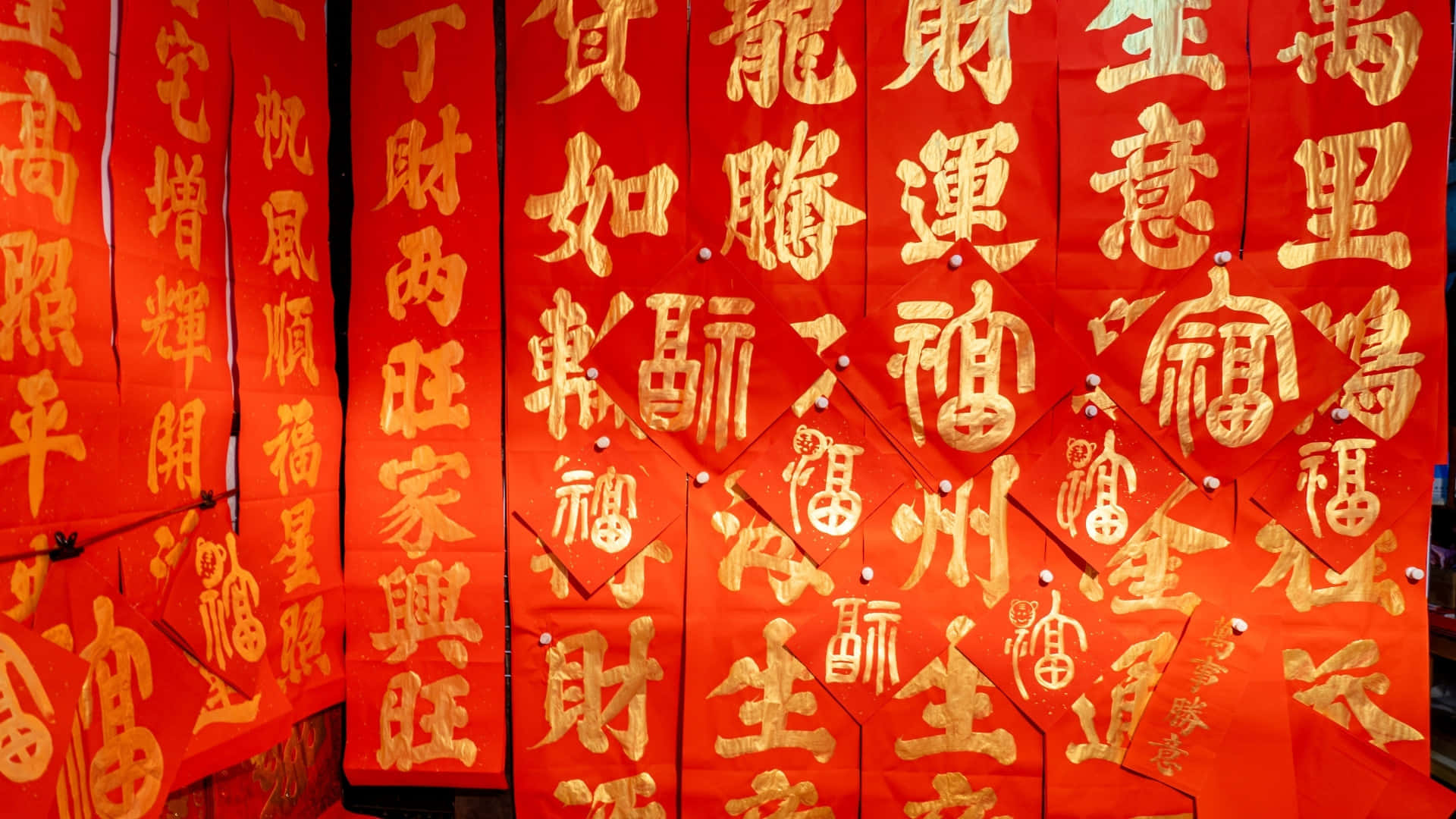 壁紙 — 鮮紅色的紙製橫幅上帶有金色中國書法，以別針固定在一起，營造出節日氣氛。