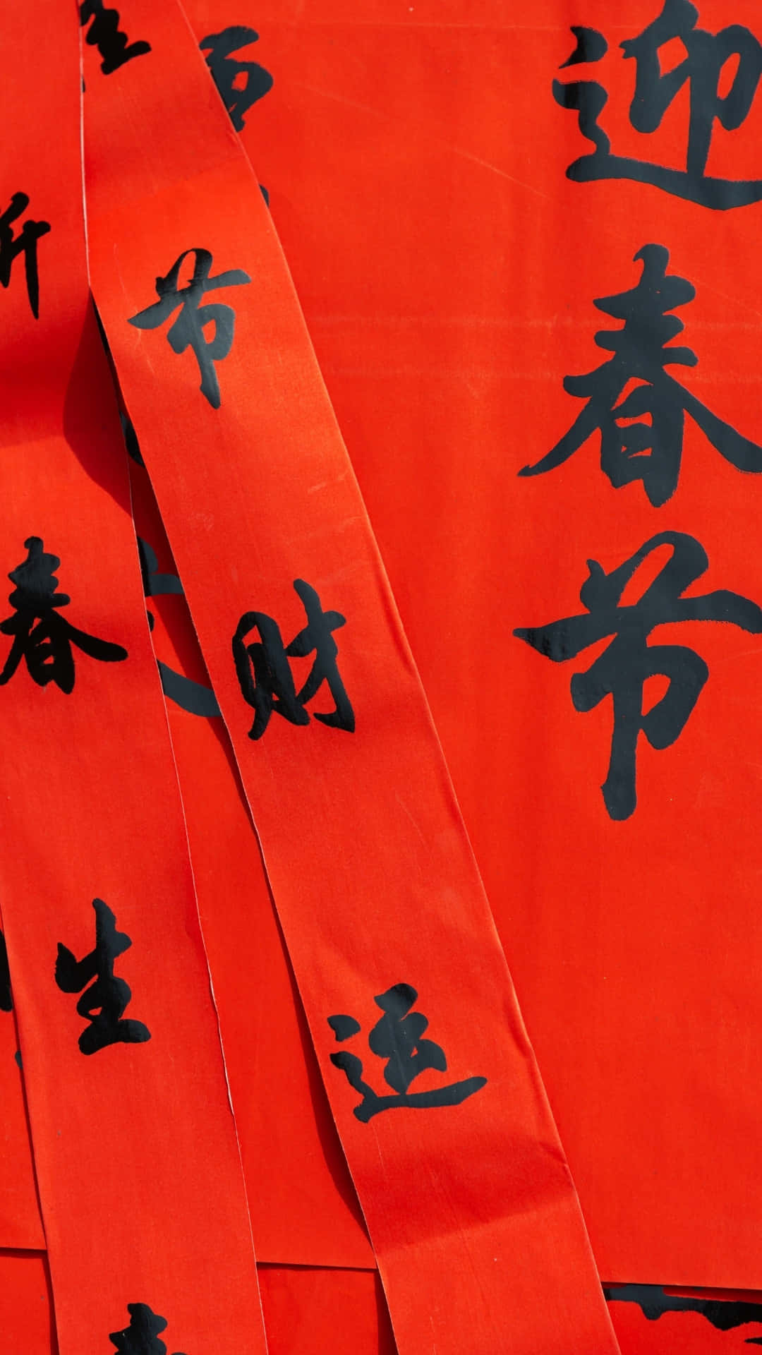  壁紙 — 鮮豔的紅色紙條，帶有粗體黑色中文書法，用於春節慶祝活動。