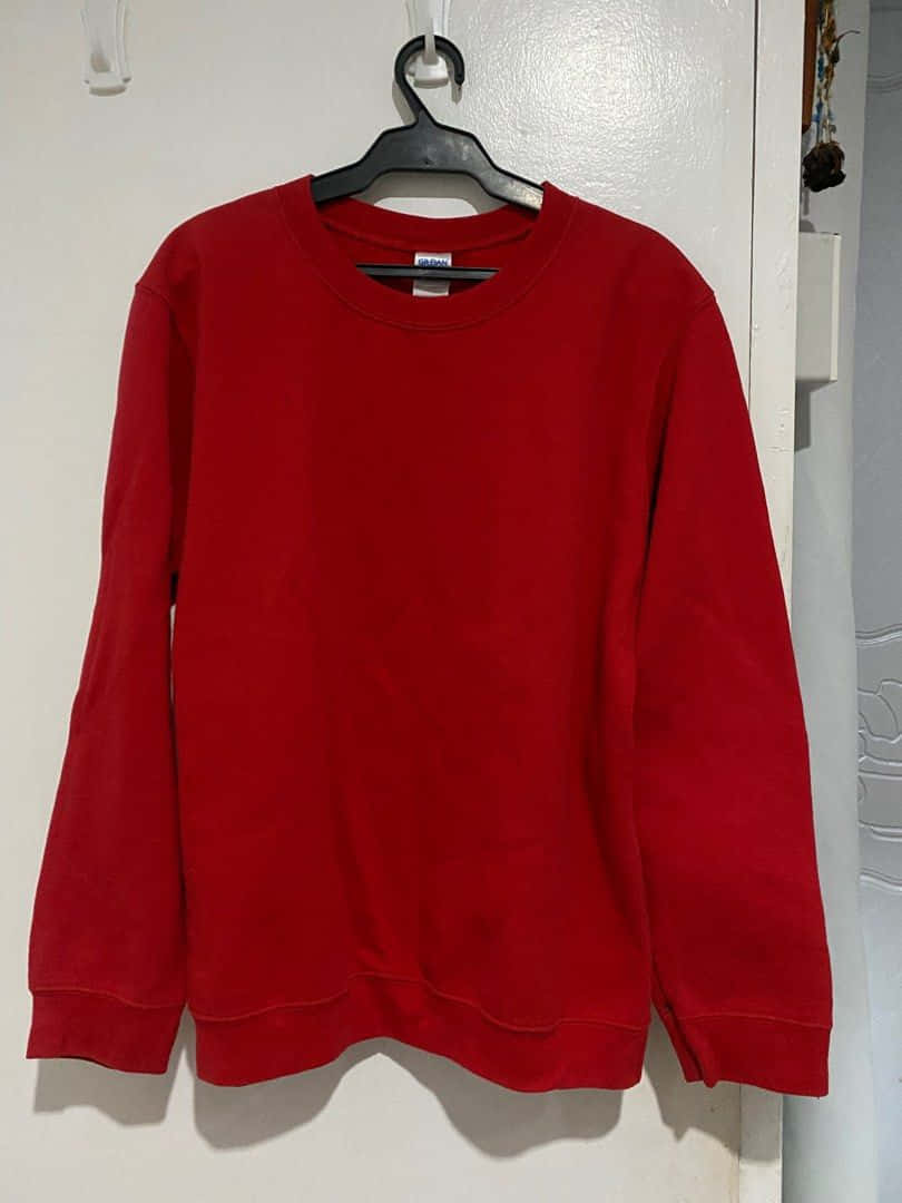Red Sweater 桌布 壁紙 — 一件鮮紅色衛衣整齊地掛在黑色衣架上，背景是純白牆壁。