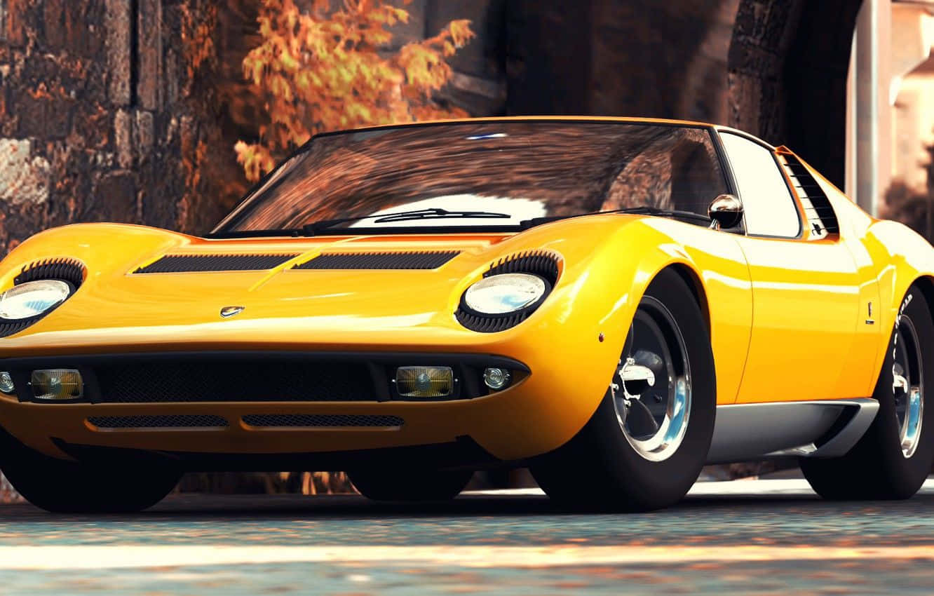 Lamborghini Miura 桌布 壁紙 — 一輛充滿活力的黃色經典跑車，帶有黑色點綴，停在鵝卵石街道上，旁邊是秋天的樹木。