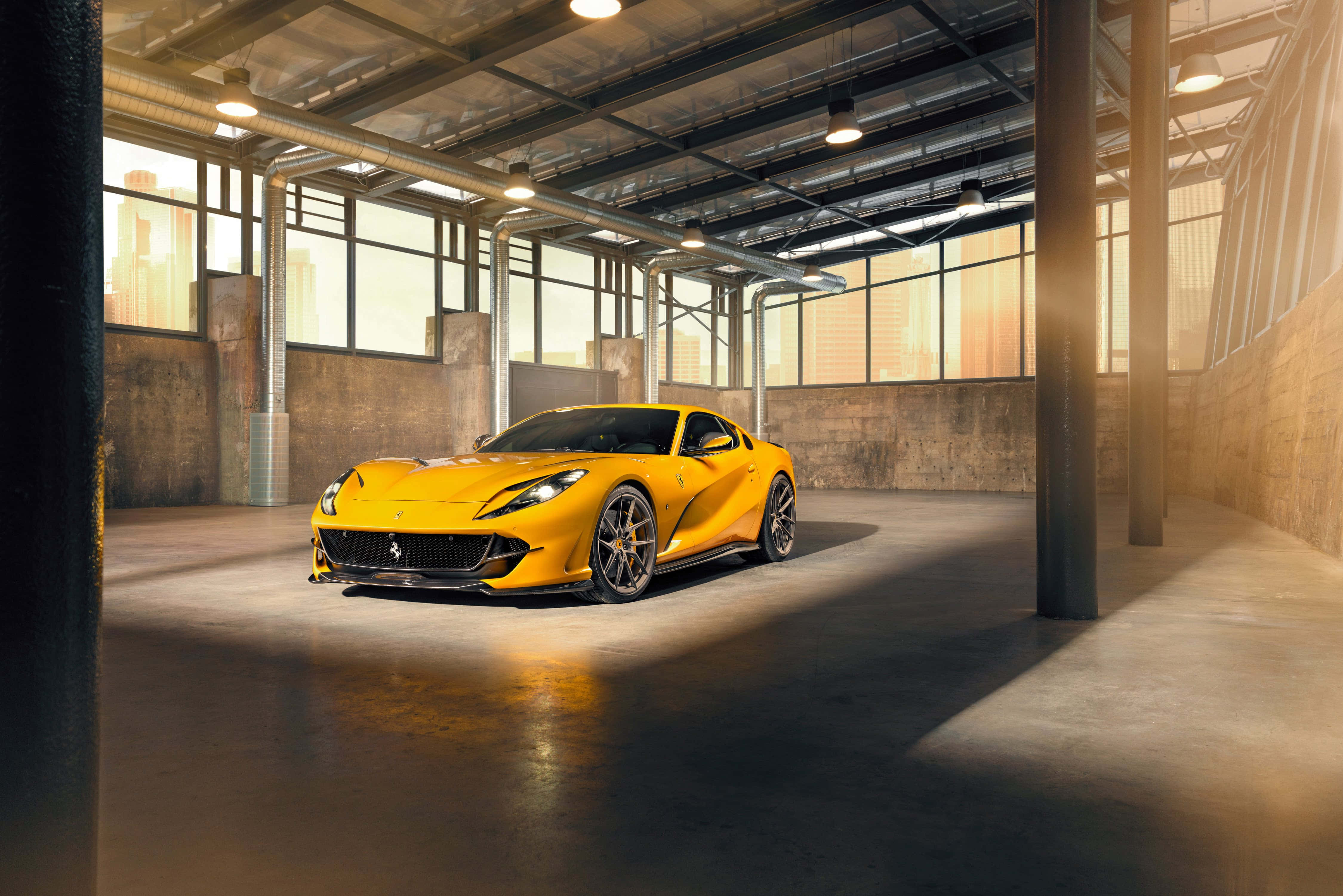 Ferrari 812 Superfast 桌布 壁紙 — 一輛充滿活力的黃色法拉利跑車在寬敞工業倉庫的大窗戶透進的溫暖陽光下閃閃發光。
