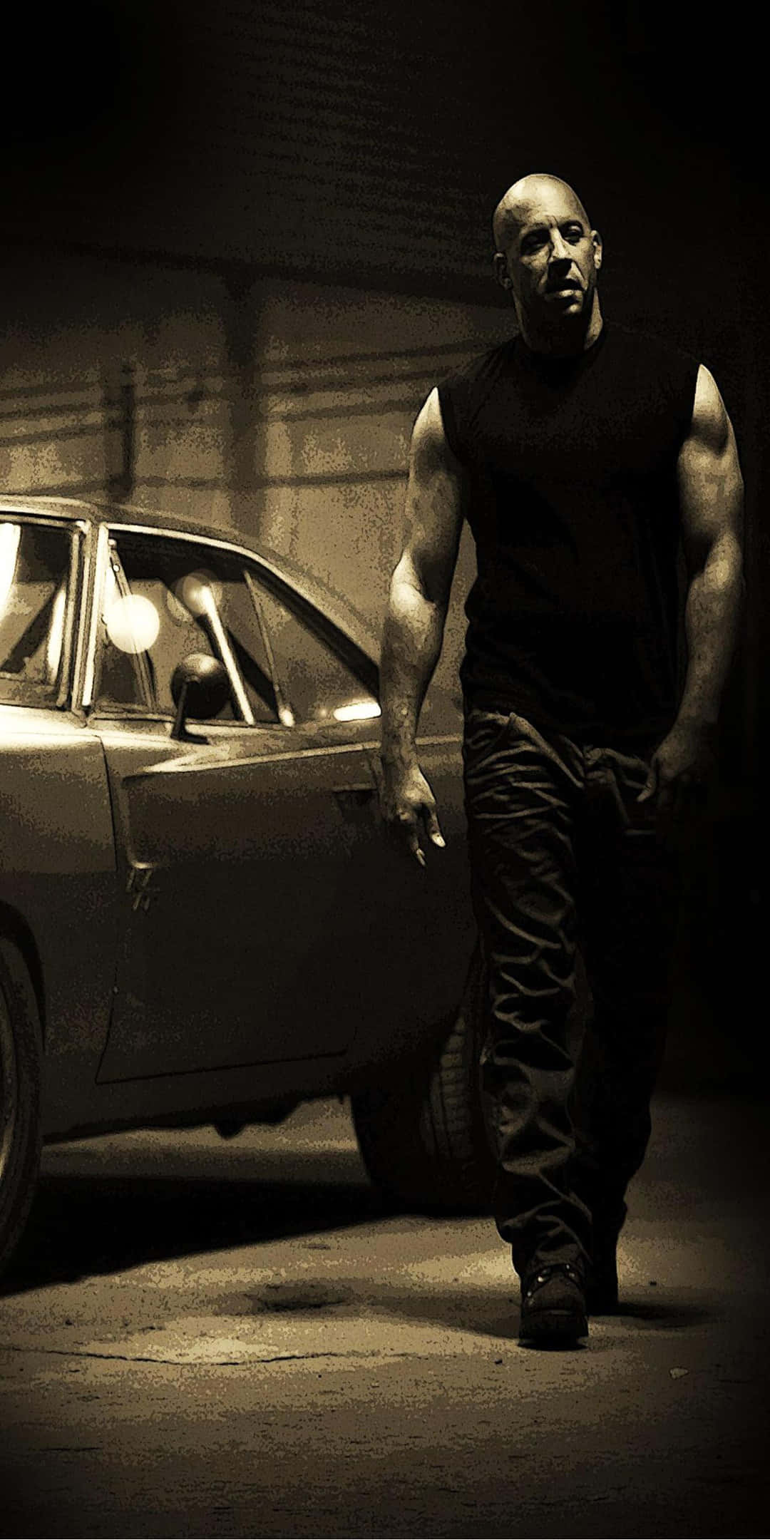 Vin Diesel 快速與狂野 Pixel 3 背景 壁紙 — 一個肌肉發達的男人穿著黑色背心，在昏暗的車庫中，伴隨著戲劇性的明暗對比燈光，自信地走在一輛復古車旁。