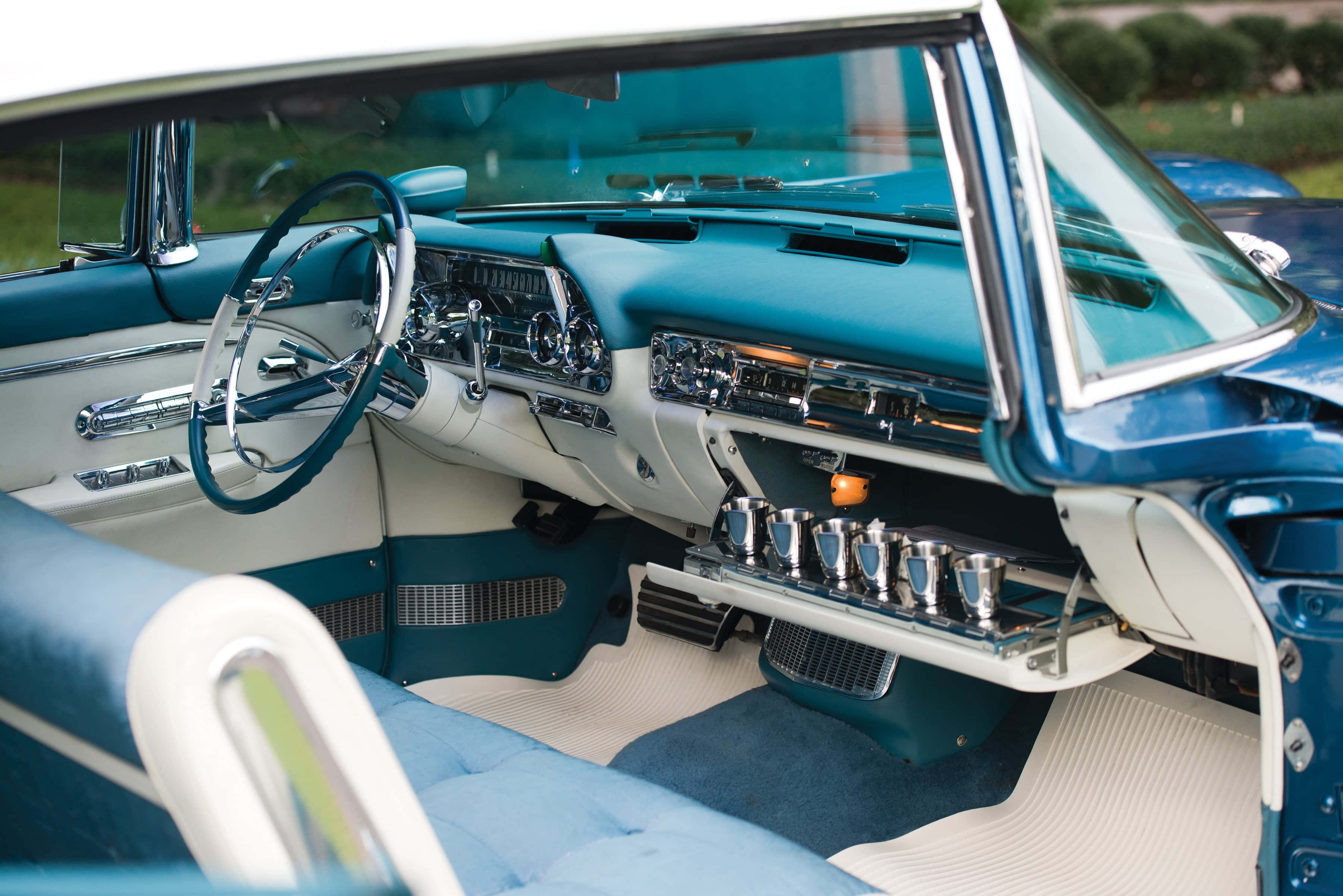 Cadillac Eldorado 桌布 壁紙 — 一輛復古車的內部展示了引人注目的藍綠色和奶油色配色方案，帶有鍍鉻裝飾和經典儀表板。