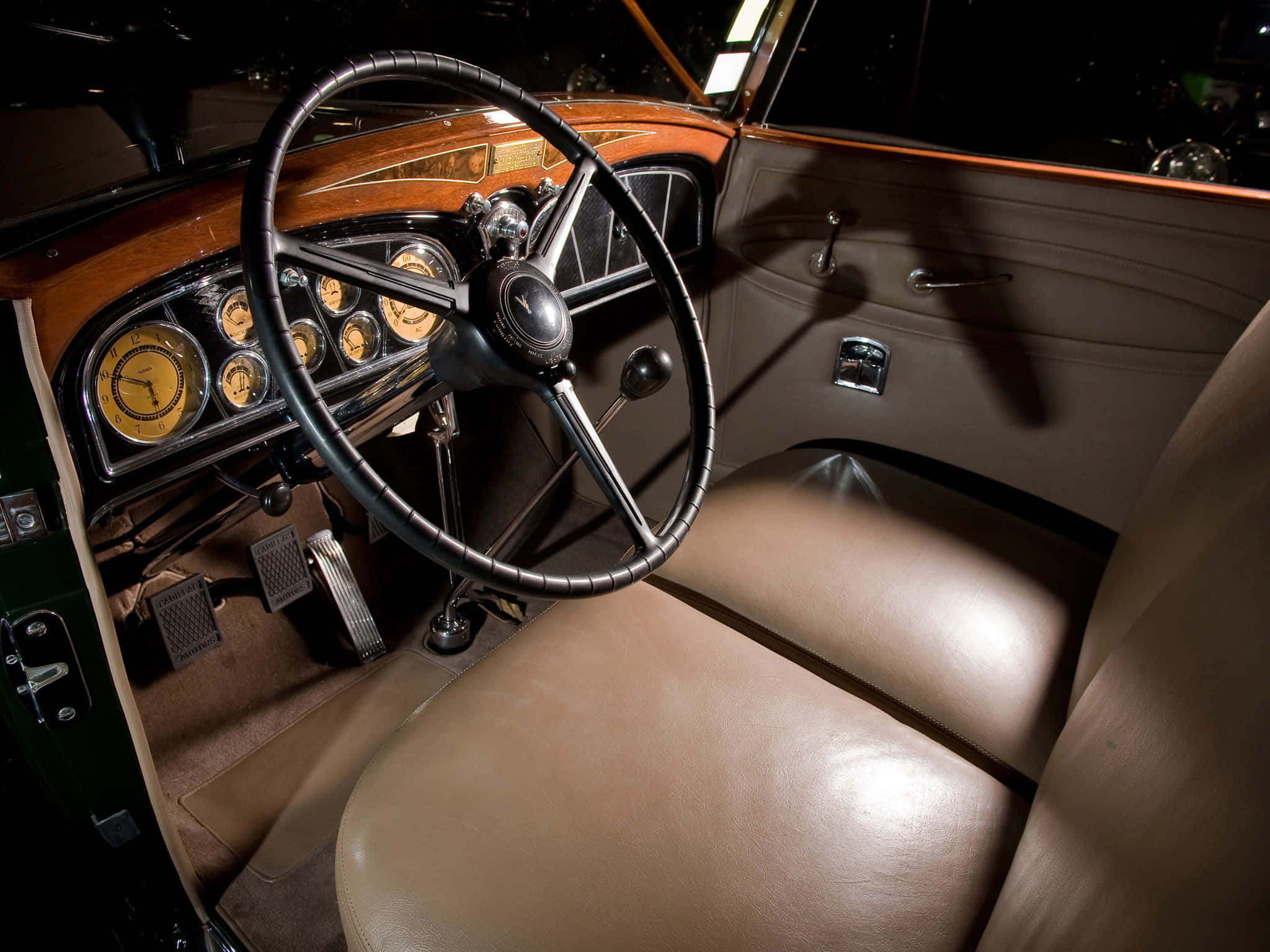 Cadillac Fleetwood 桌布 壁紙 — 一輛復古車的豪華內飾，配有棕褐色皮革座椅、木質飾邊和溫暖聚光燈下發光的模擬儀表。