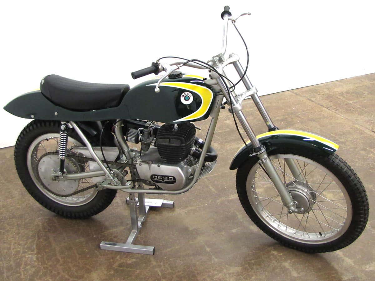 Ossa Motorcycle 桌布 壁紙 — 復古綠色和黃色BMW R50/5電單車在工作室的支架上，背景為混凝土地板和白色牆壁。