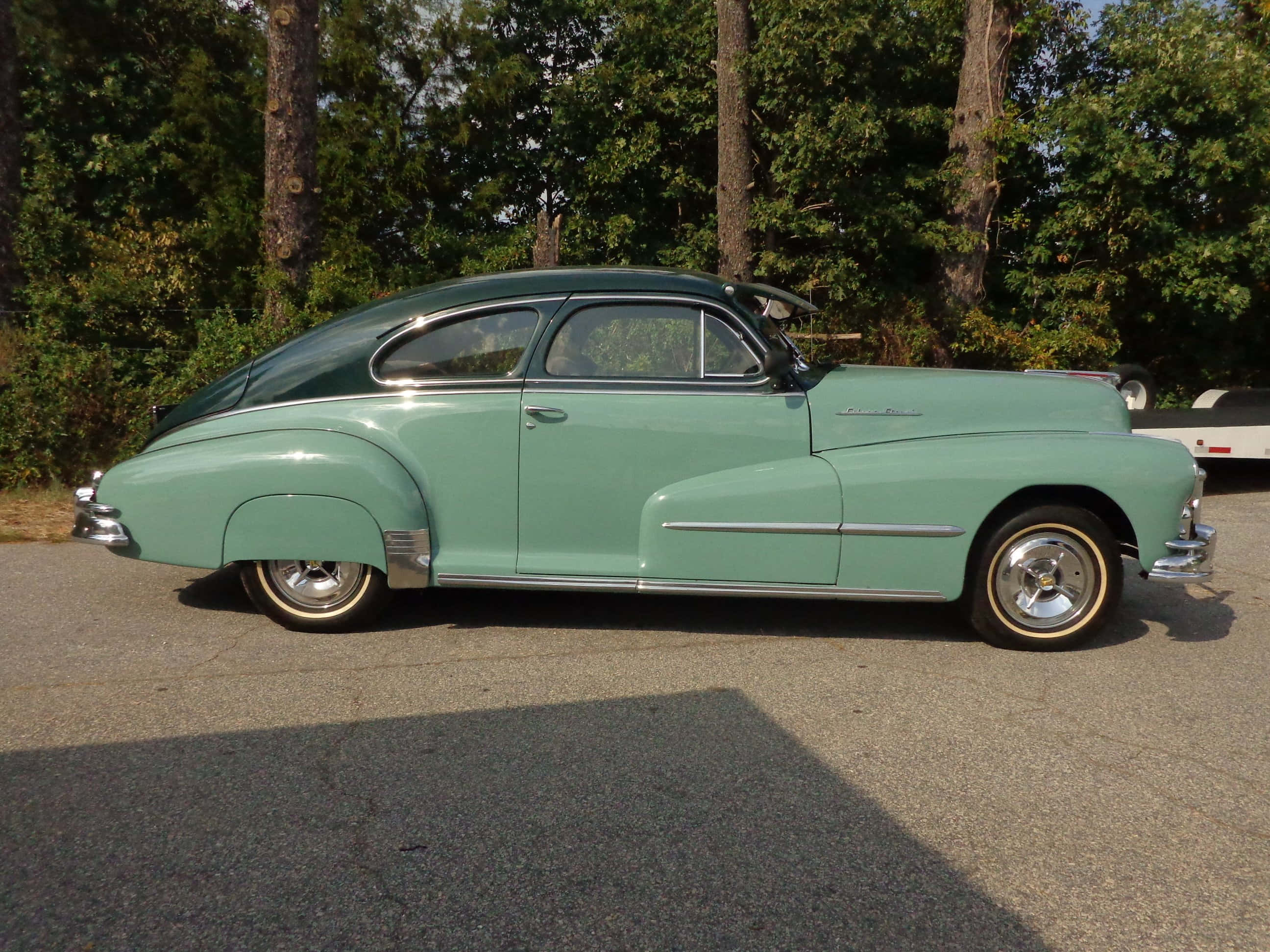 Pontiac Streamliner 桌布 壁紙 — 一輛復古薄荷綠色雙門轎跑車，帶有鍍鉻飾條，停在瀝青路面上，背景有樹木，光線明亮。