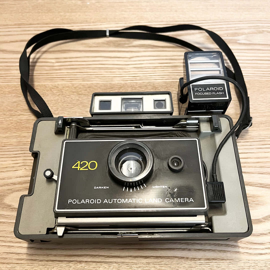  壁紙 — 一部復古的Polaroid 420自動即影即有相機，附有閃光燈，放在淺色木質表面上。