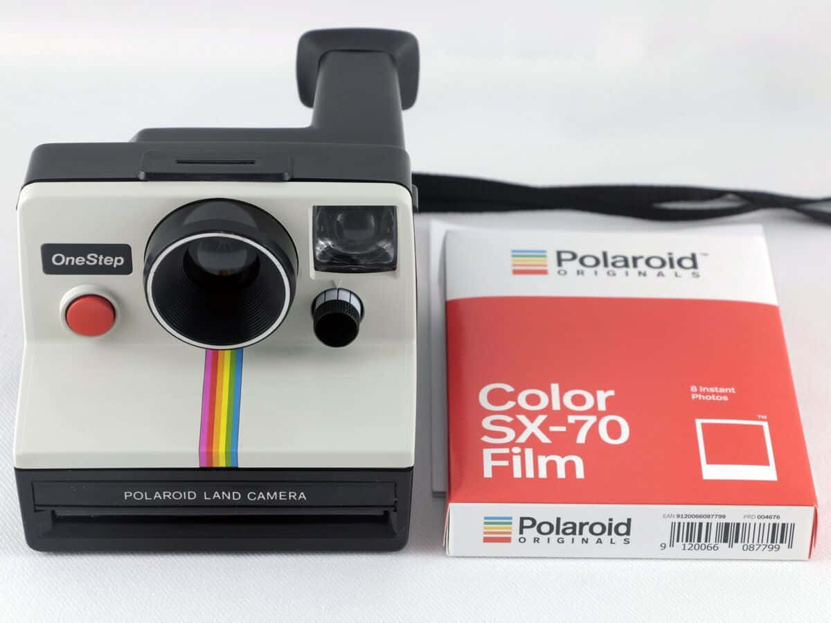  壁紙 — 一部帶有彩虹條紋的復古Polaroid OneStep相機，旁邊放著一盒紅色Color SX-70菲林，置於白色表面上。