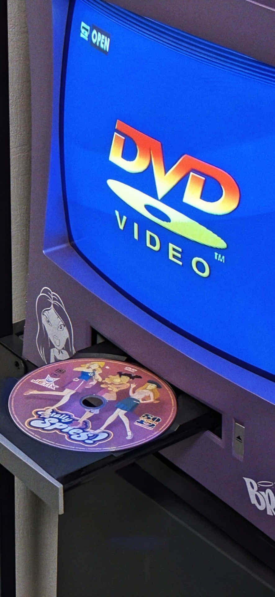  壁紙 — 一部復古紫色DVD播放器正在彈出色彩繽紛的「Bratz」DVD光碟，屏幕上顯示發光的DVD Video標誌。