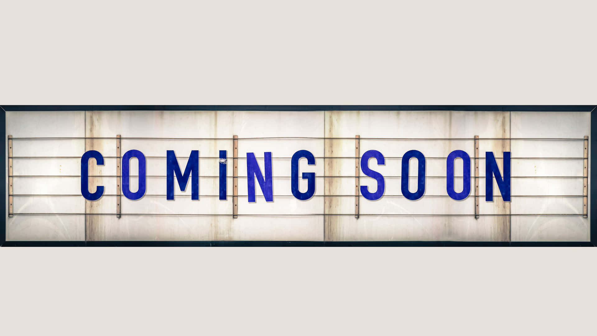 一個復古發光招牌，上面用藍色字母寫著「COMING SOON」。