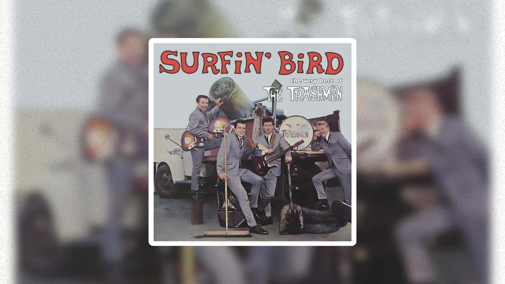 壁紙 — 復古衝浪搖滾樂隊 The Trashmen 穿著灰色西裝，圍繞著一輛帶有衝浪板和樂器的復古卡車擺姿勢。