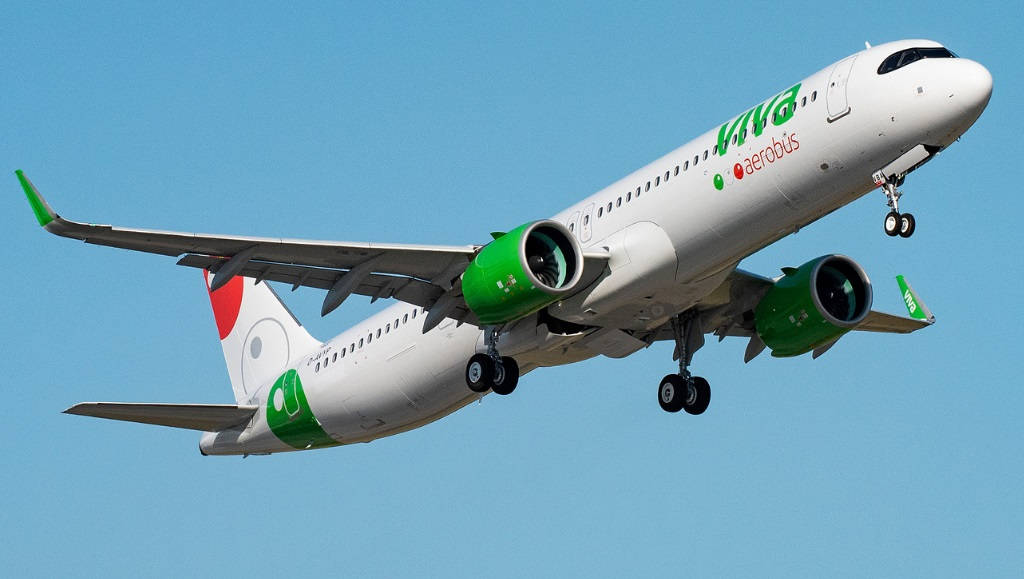Viva Aerobus 飛行於藍天之中 壁紙 — 一架白色和綠色的Viva Aerobus飛機放下起落架，在晴朗的藍天中翱翔。