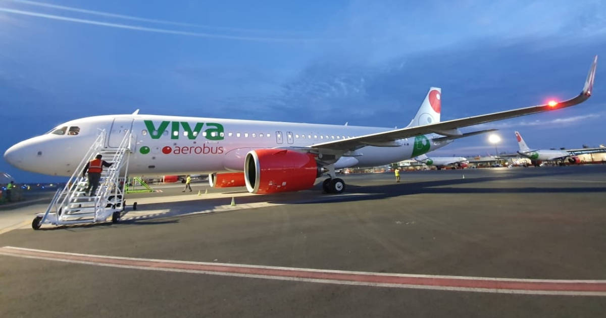 夜空下帶階梯的Viva Aerobus 壁紙 — 一架帶有紅色引擎和綠色品牌的Viva Aerobus飛機，在黃昏時停在機場停機坪上，附近有地勤人員。