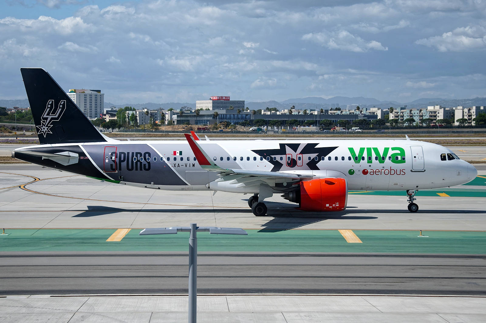 Viva Aerobus飛機在停機坪上，帶有馬刺隊標誌，天空多雲