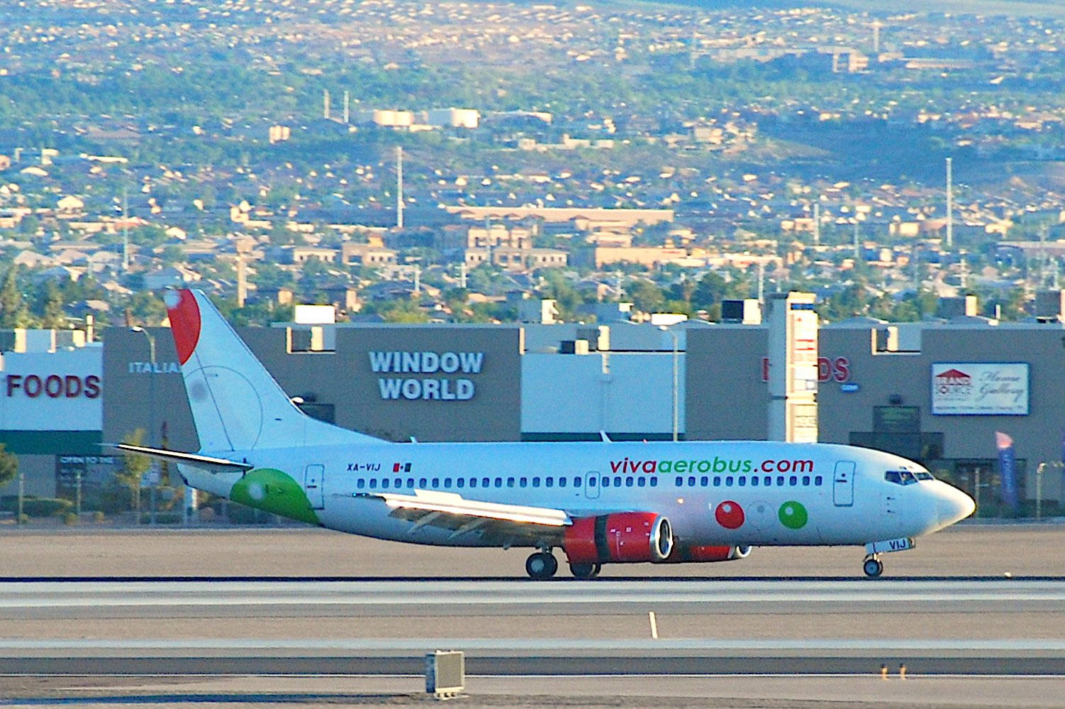Viva Aerobus飛機在商業建築附近的機場跑道上滑行。