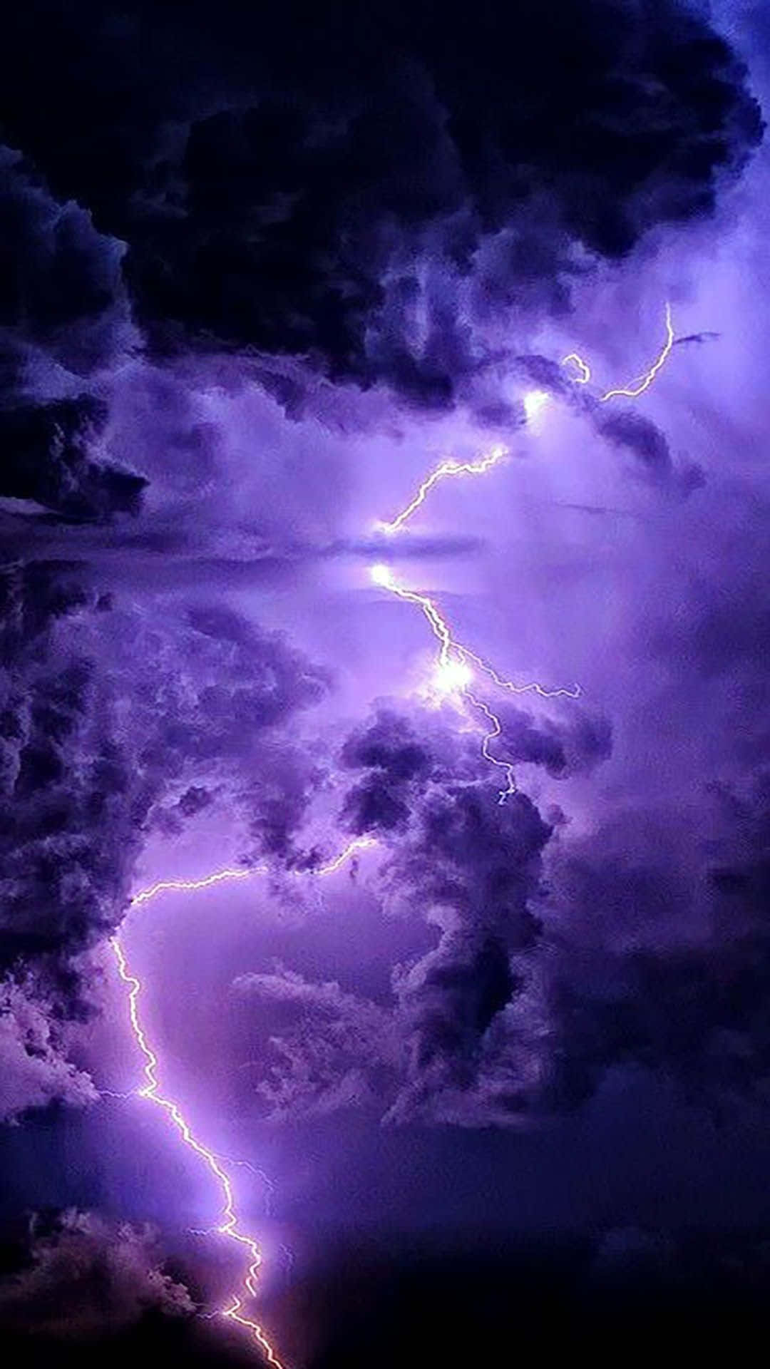 Purple Lightning 桌布 壁紙 — 生動的紫色閃電穿過動盪的暴風雲，在戲劇性的夜空中分叉。