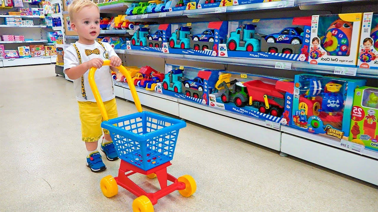 幼兒在玩具店通道推著玩具購物車