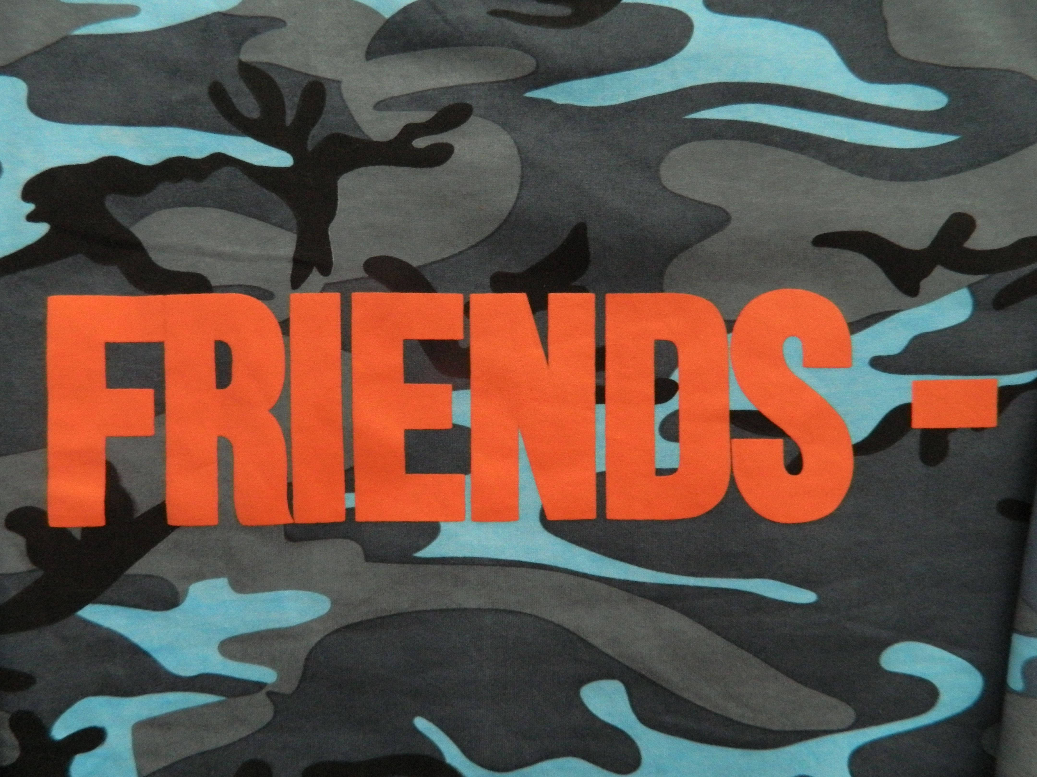 VLONE Friends 迷彩布料 壁紙 — 大膽的橙色「FRIENDS」文字主導了灰藍色和黑色迷彩布料背景。