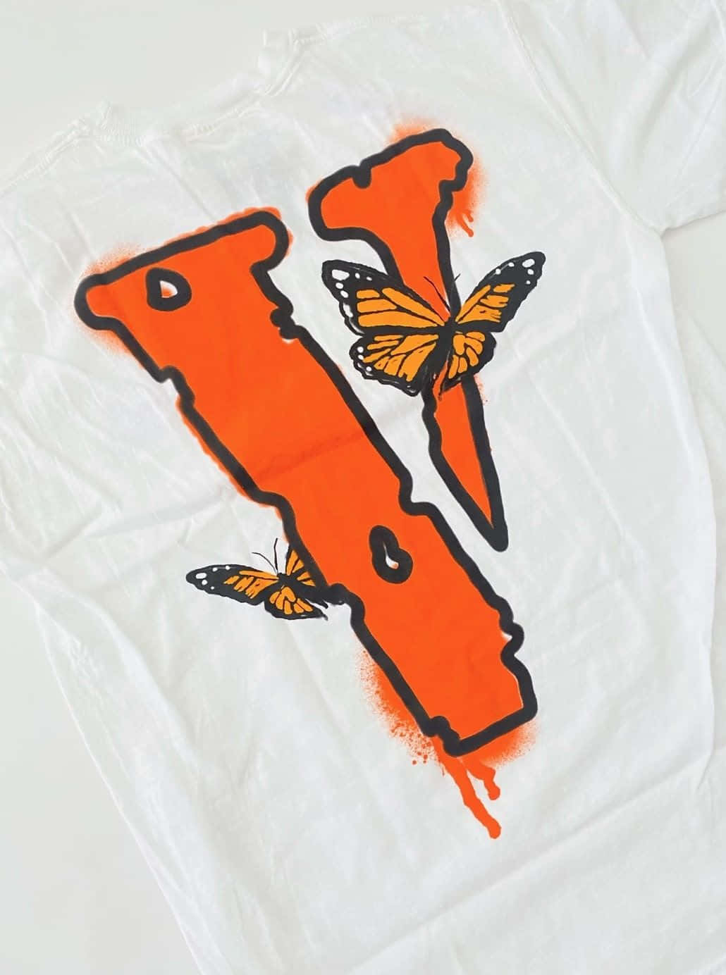 Vlone iPhone 蝴蝶白T恤壁紙 壁紙 — 一件白色T恤上有一個大膽的橙色噴漆字母V，帶有黑色輪廓，兩隻帝王蝶棲息在上面。