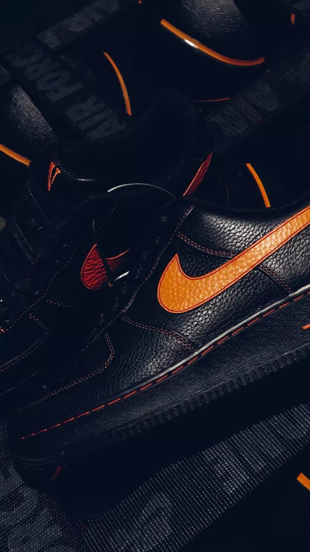 VLONE 黑色 Air Force 1 壁紙 — 黑色Nike Air Force 1運動鞋特寫，帶有醒目橙色點綴和紅色縫線，在戲劇性燈光下拍攝。