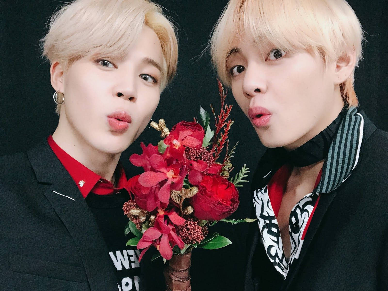 Vmin 黑紅配色 壁紙 — 兩名金髮男子在黑色背景前手持鮮豔的紅色花束，做出鬼臉。