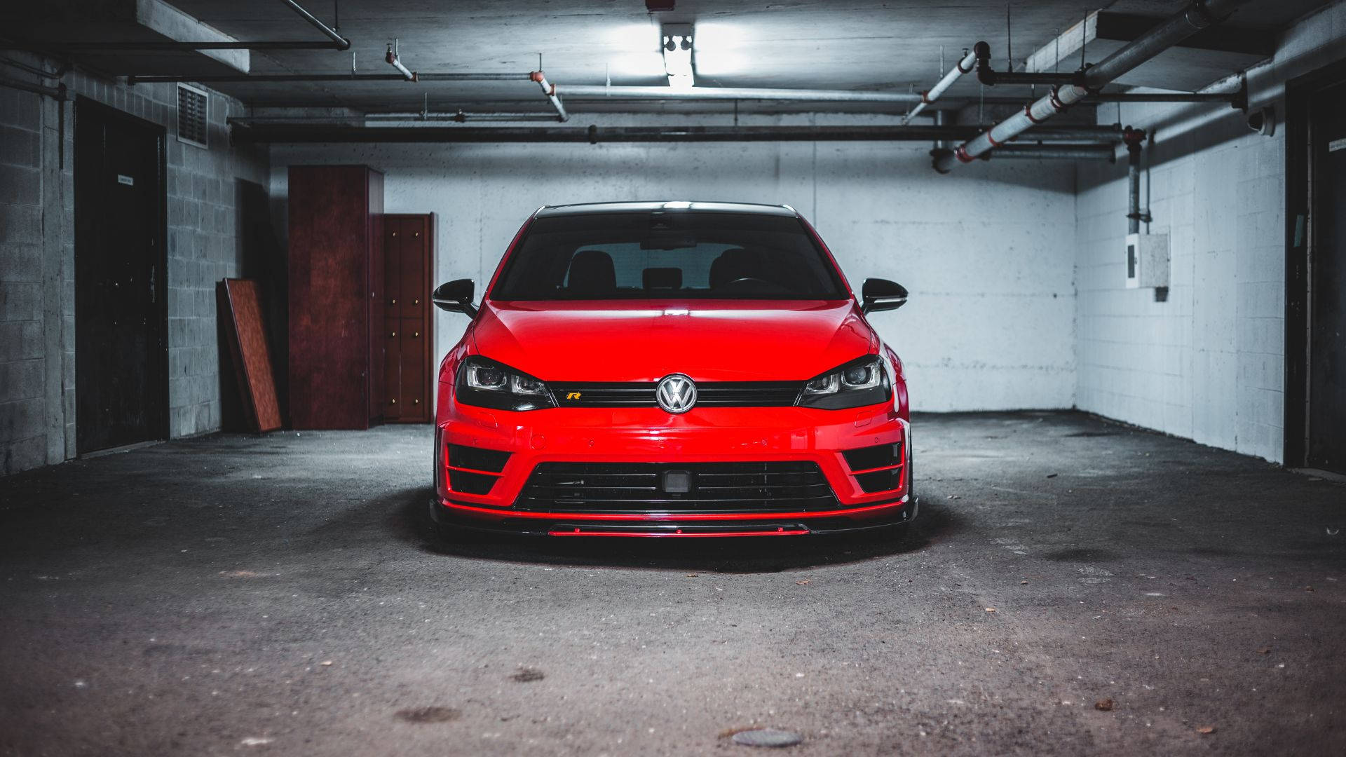 現代車庫中的經典 Volkswagen Golf GTI 壁紙 — 一輛鮮紅色的福士 GTI R 停放在昏暗的混凝土車庫中央，在工業照明下。