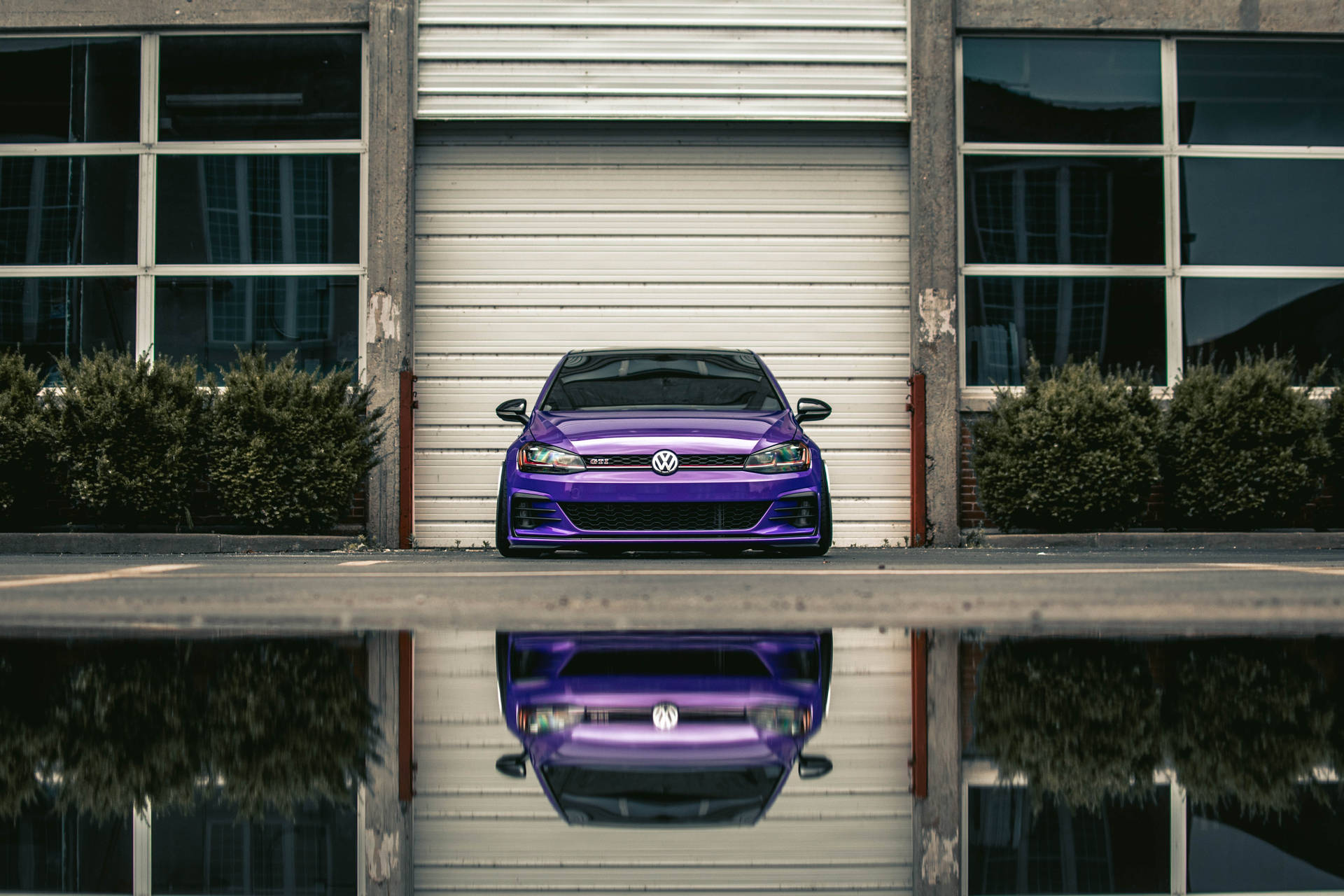 紫色 Volkswagen GTI 停在車庫前，帶有水坑倒影