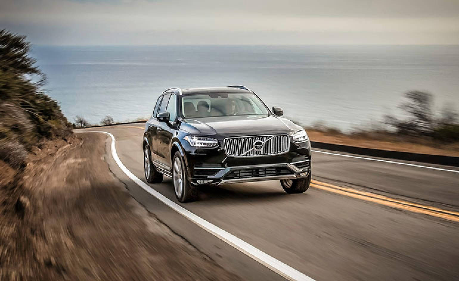 黑色Volvo SUV在海景海岸公路上行駛。