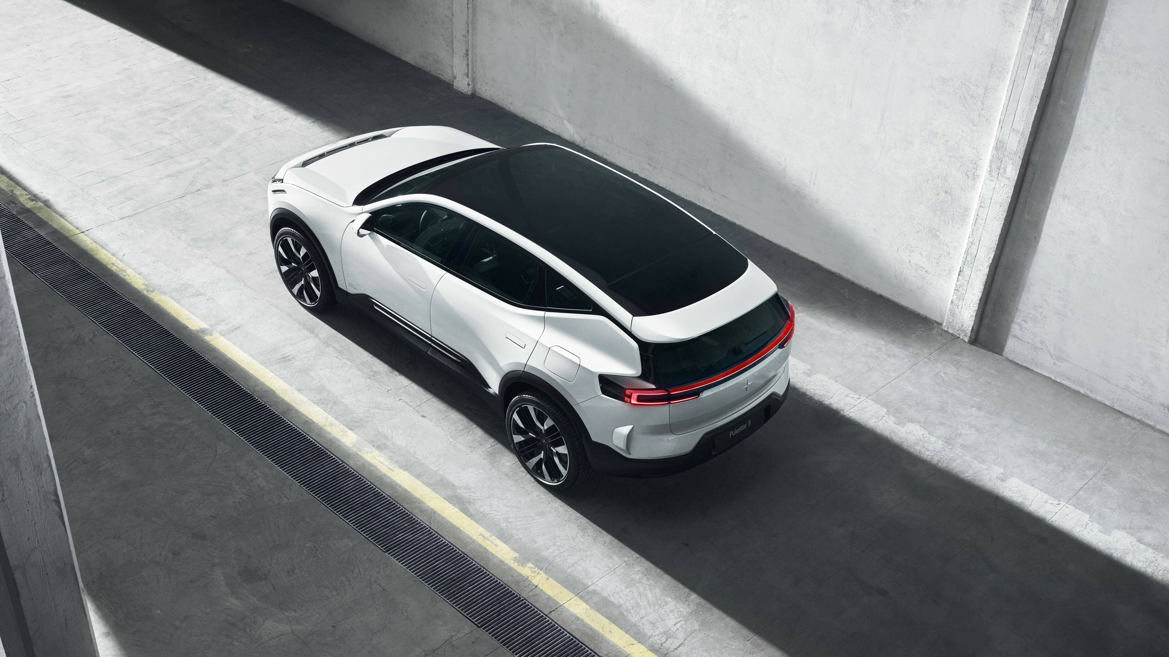 Volvo極星揭幕 壁紙 — 一輛時尚的白色電動SUV，配備黑色車頂和紅色尾燈，停在明亮的日光下的混凝土坡道上。