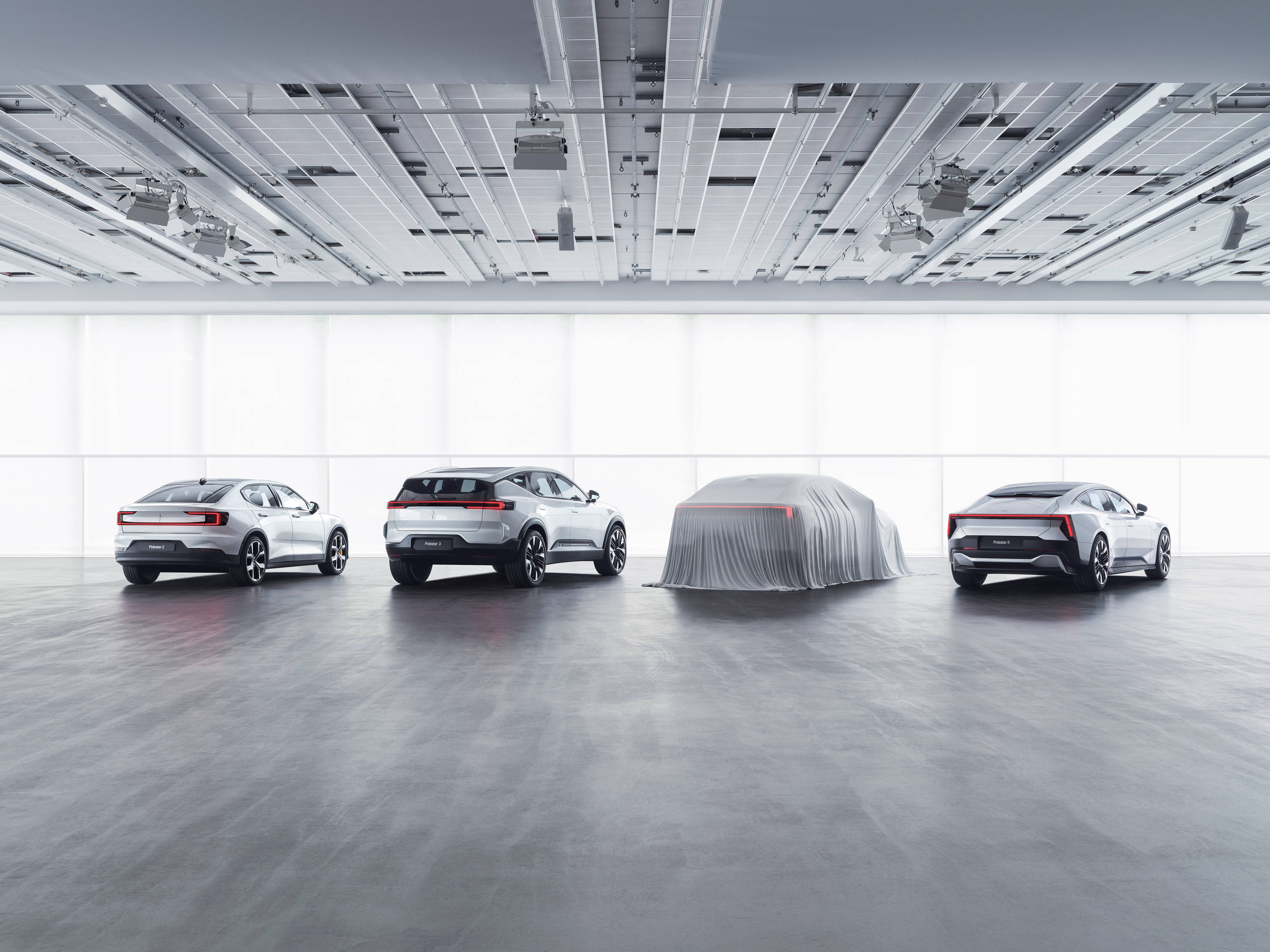 Volvo極星車款系列 壁紙 — 四輛時尚的銀色電動車在極簡白色工作室中展示，其中一輛被布料覆蓋。